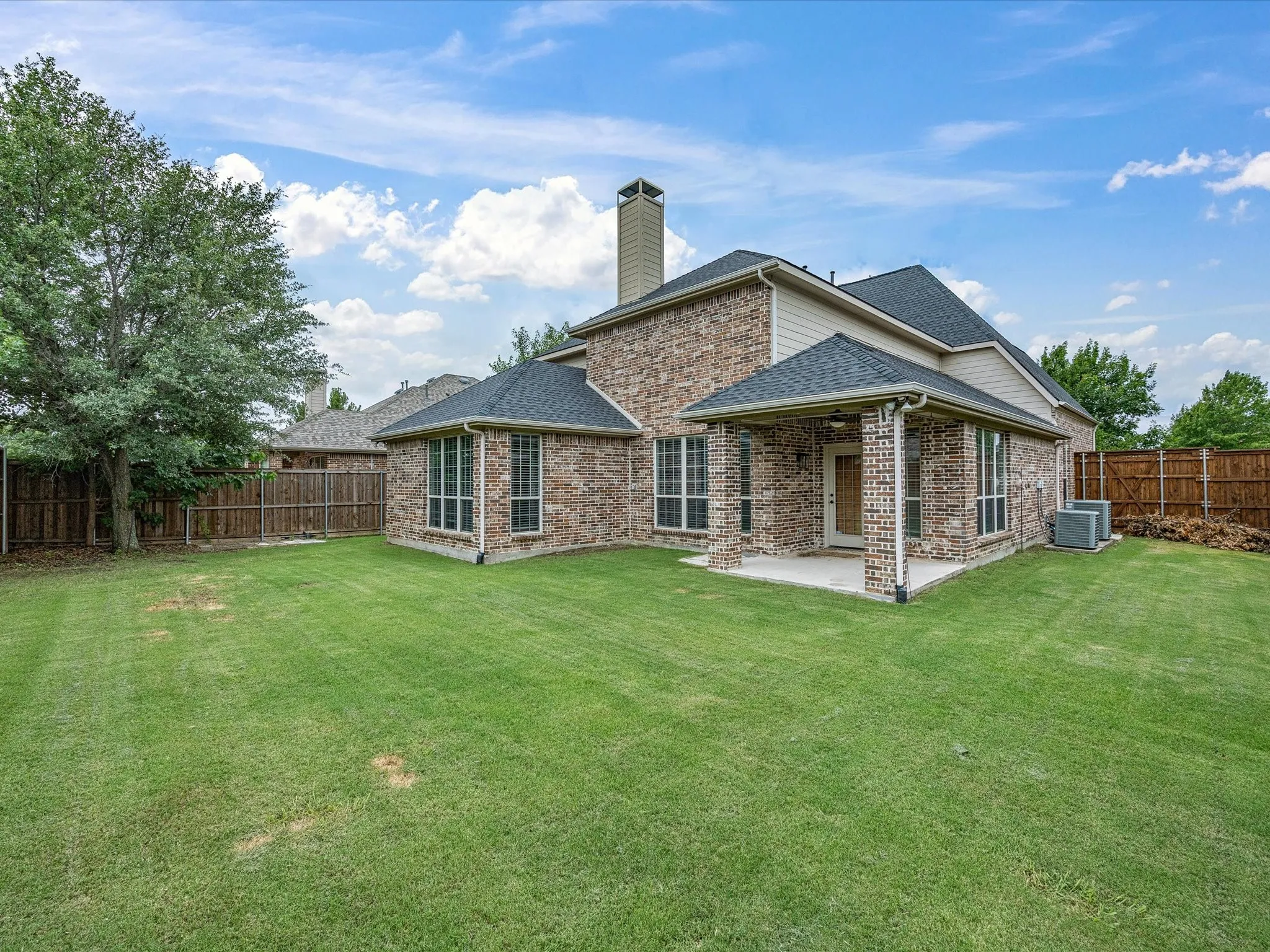 Expansive green lawn with a brick exterior featuring multiple large windows
