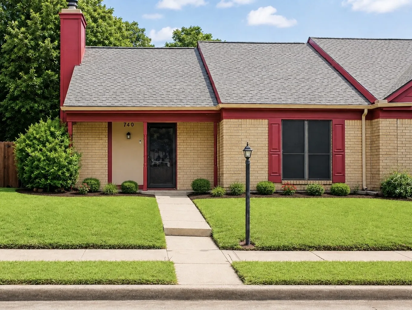 Brick facade residence featuring a front entry with a black screen door, a red-painted chimney, and a window with red shutters