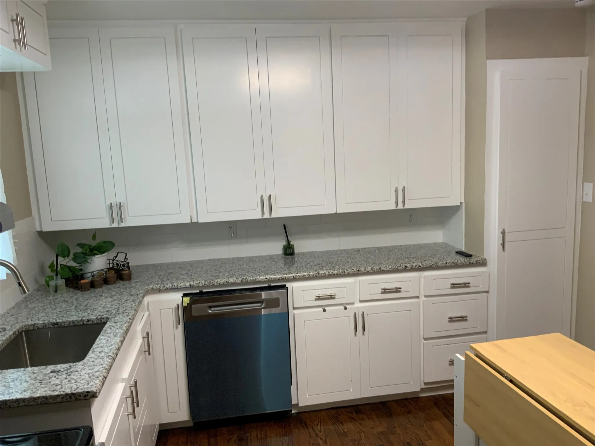 Kitchen featuring white shaker cabinetry, granite countertops, stainless steel undermount sink, stainless steel dishwasher, and wood-finish flooring