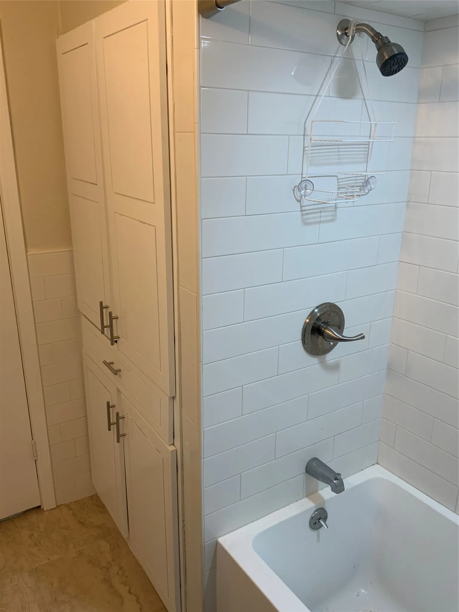 Bathroom featuring white subway tile surround, brushed nickel fixtures, and a white bathtub