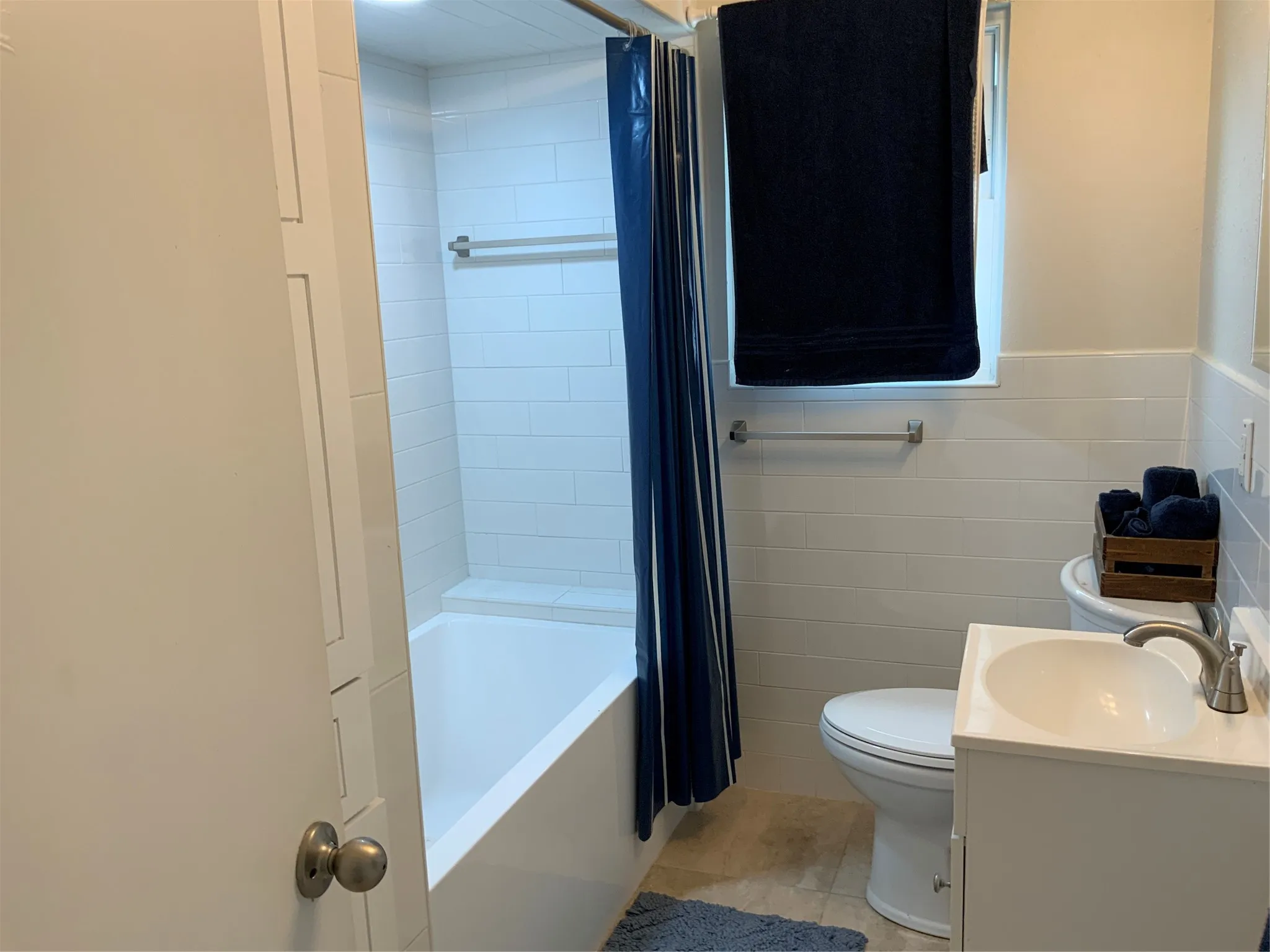 Bathroom featuring a white subway tile tub surround, white bathtub, vanity with integrated sink, and white ceramic tile half-wall