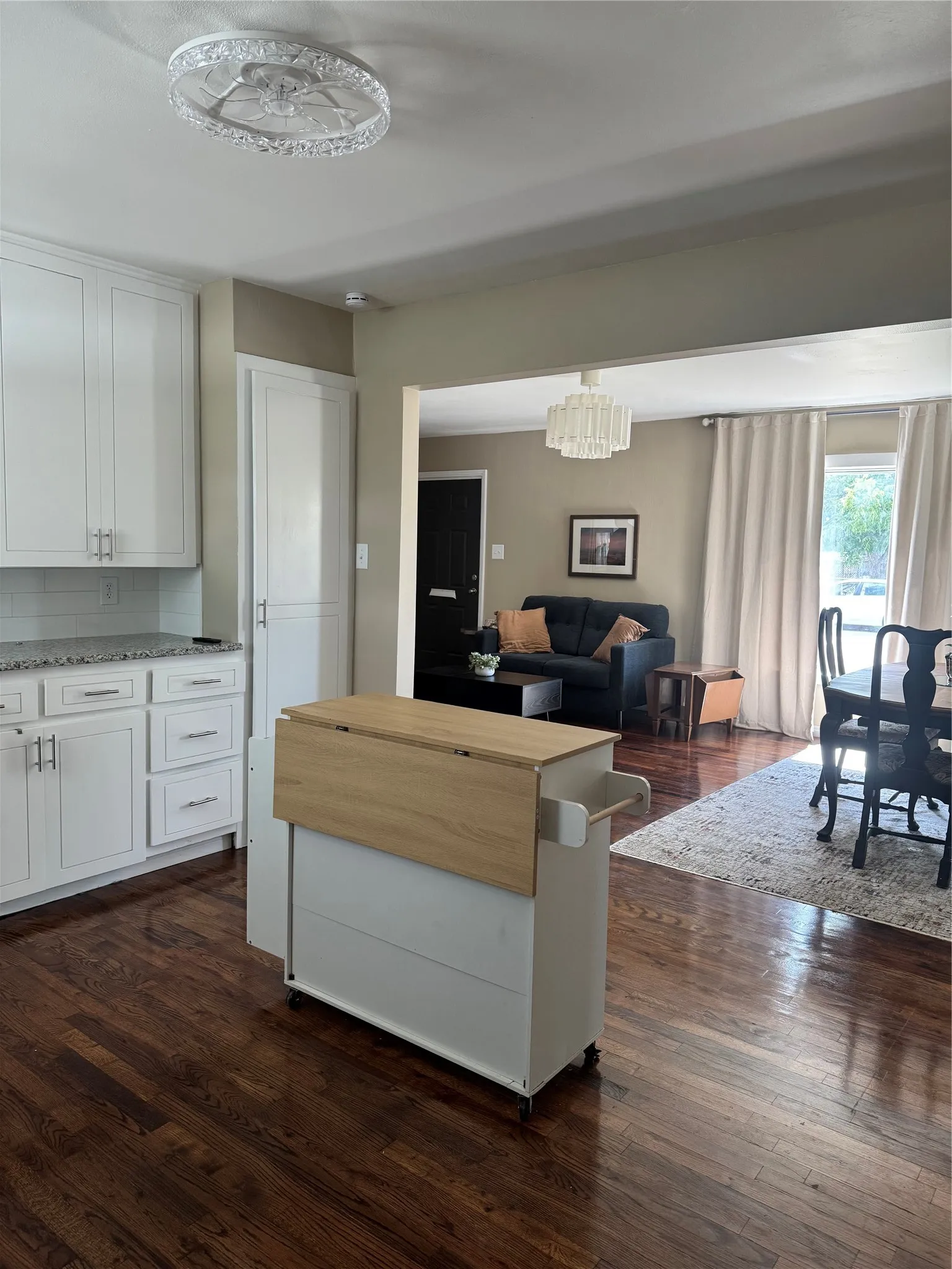 Kitchen featuring wood-finish flooring, white cabinetry with silver hardware, light-toned countertops, and a subway tile backsplash