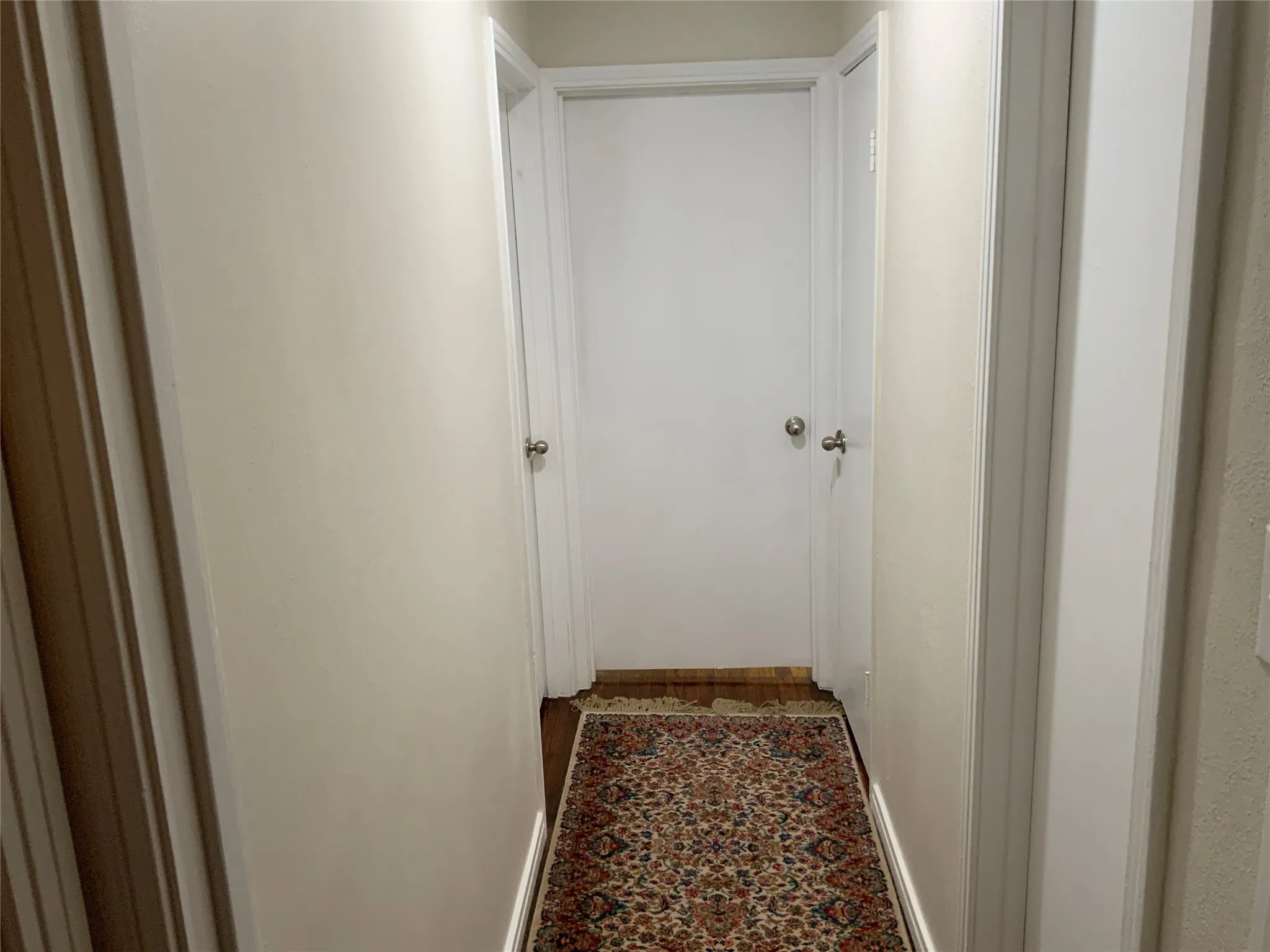 Hallway featuring light-toned walls, white trim, and wood-finish flooring