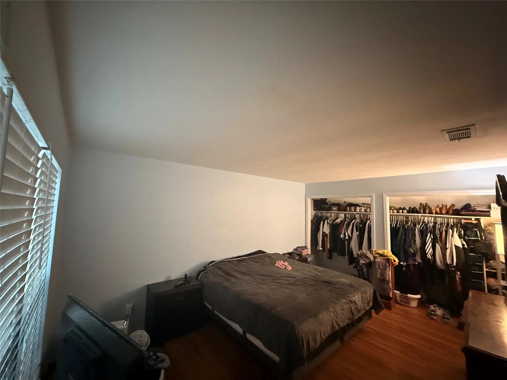 Hardwood flooring throughout featuring two open closet spaces with built-in shelving and clothing rods