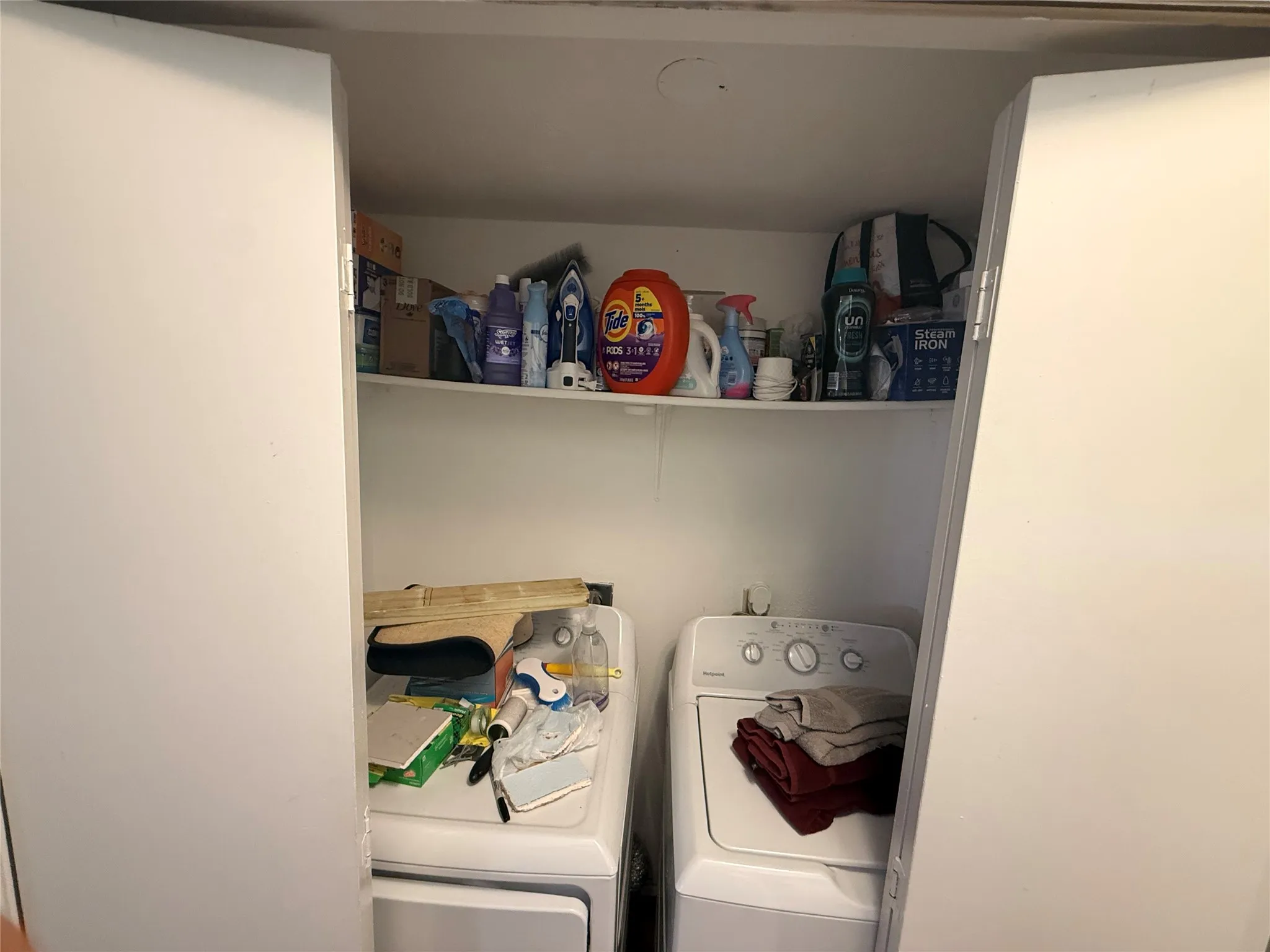 Laundry area featuring a top-loading washer, front-loading dryer, and overhead shelving