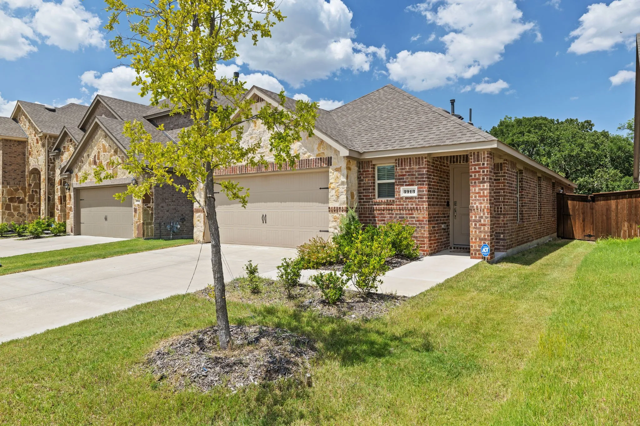 Welcome home to 3913 Nature Court! Brick and stone veneer exterior featuring a covered entry, concrete driveway, and a two-car garage