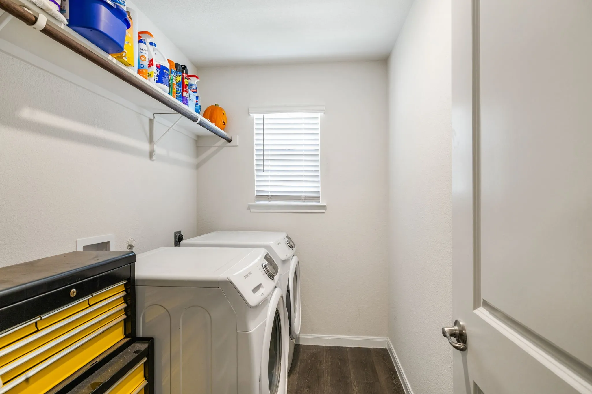 30. Dedicated laundry area featuring wood-finish flooring and a window with blinds with space for extra freezer.