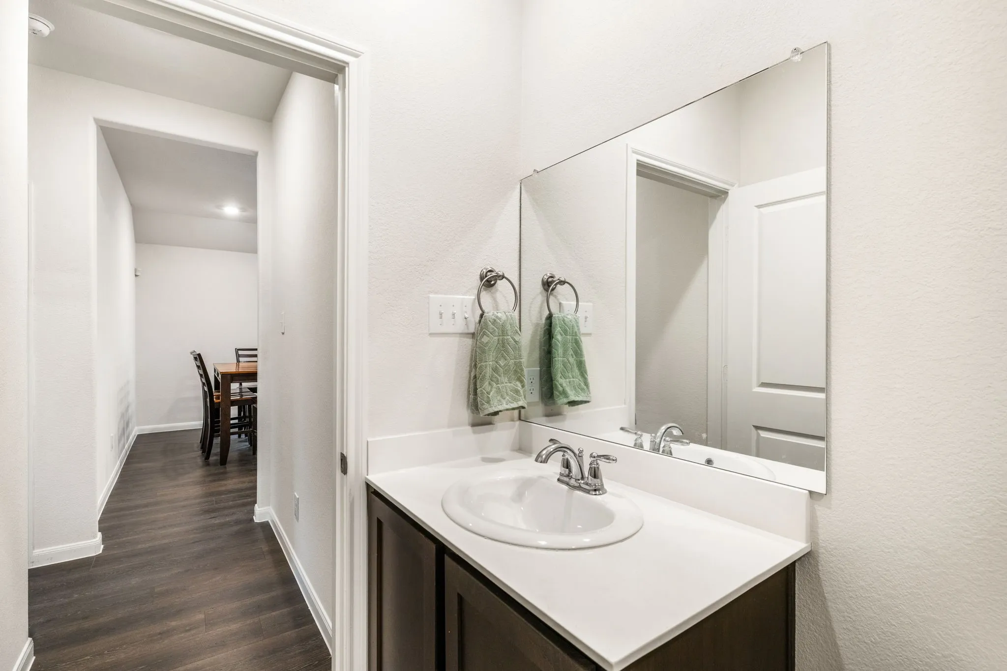 Full bathroom with vanity featuring a white countertop, dark cabinetry, and large mirror.