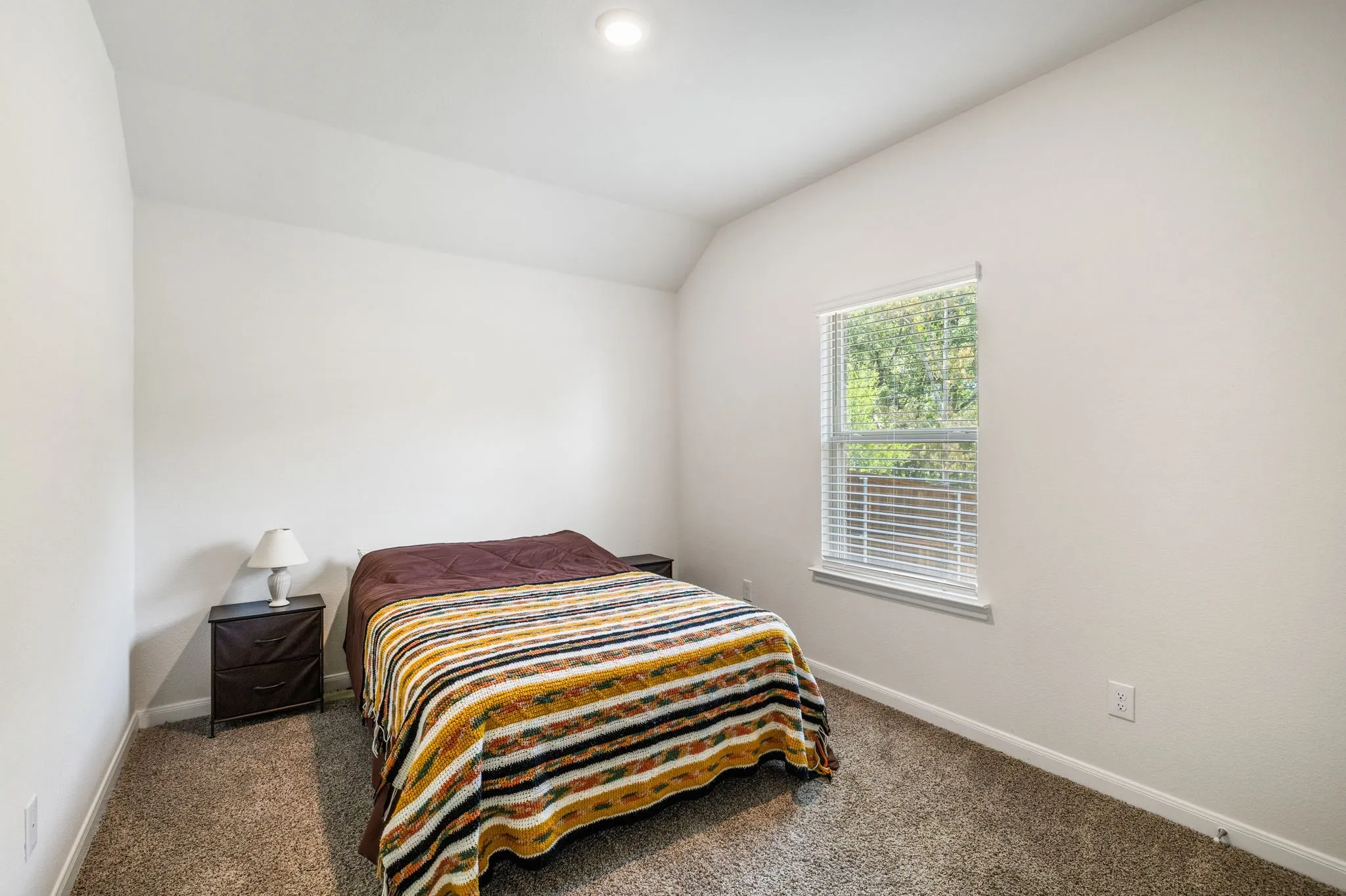 Bedroom #2 featuring carpet flooring, white wall finishes, and large window letting in natural light.