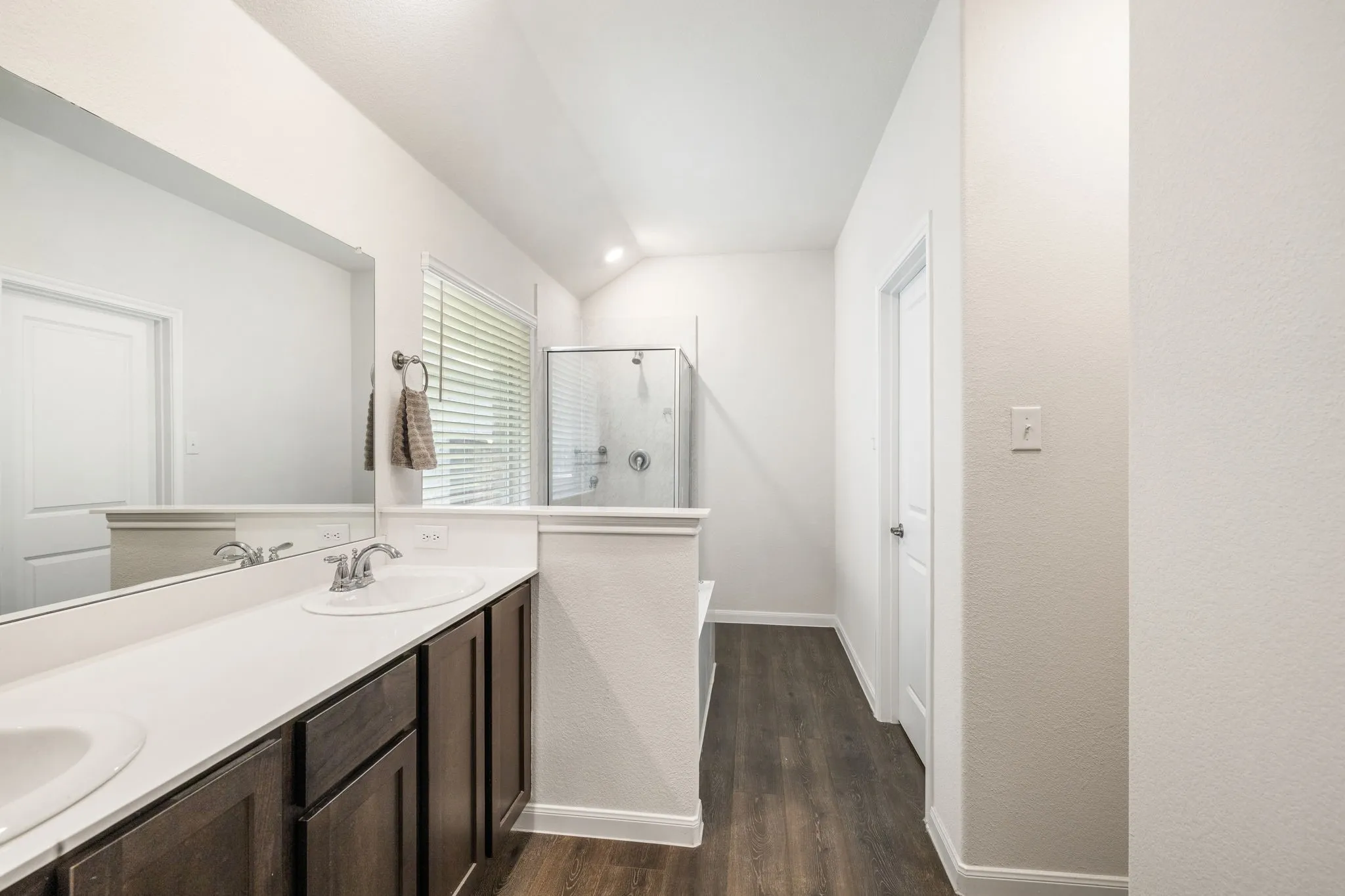 Primary bathroom features a separate stall shower and garden tub, double vanity, lofted ceiling, luxury vinyl plank flooring, and walk-in closet.