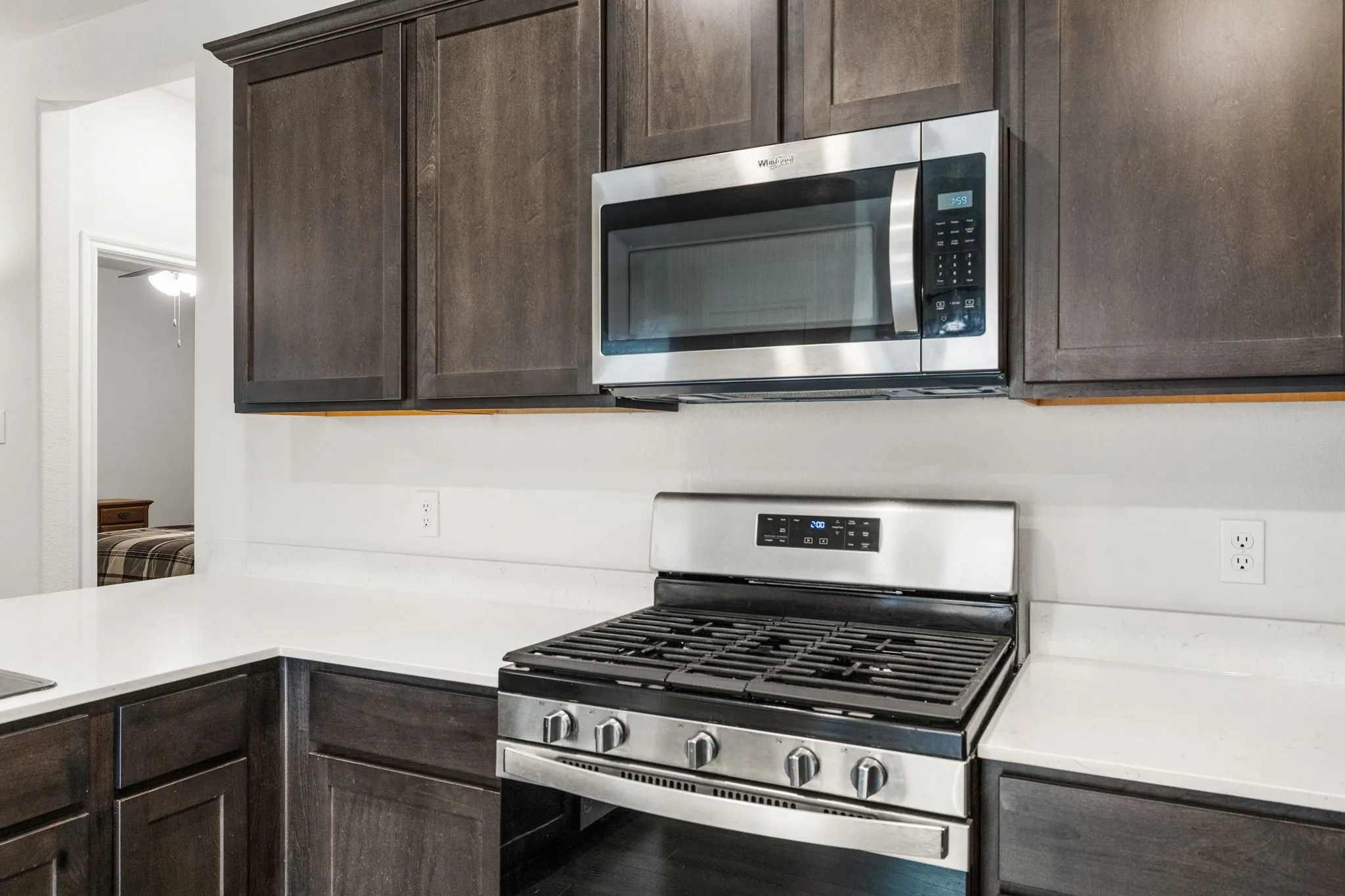 Enjoy meal prep in this modern kitchen with dark wood-finish cabinetry, stainless steel microwave, and stainless steel gas range.