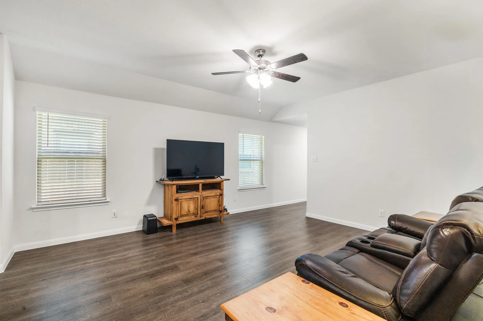 Living room looking toward front entry hallway, featuring healthy amount of natural light, luxury vinyl plank floors, and a ceiling fan