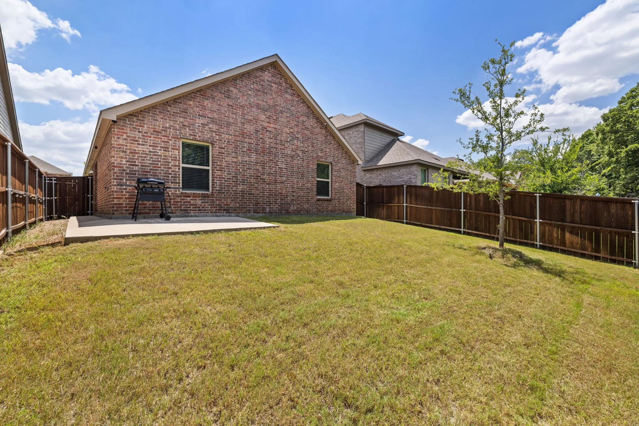 Back of property with brick siding, a patio, and a fenced backyard