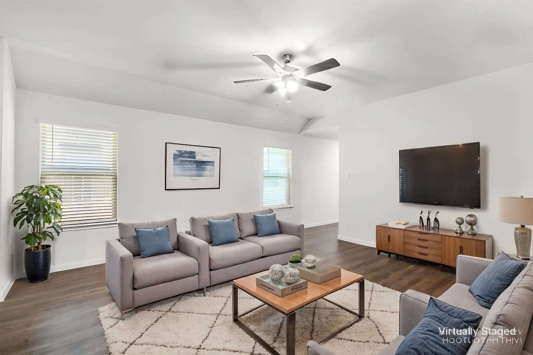 Virtually staged - Living room looking toward front entry hallway, featuring healthy amount of natural light, luxury vinyl plank floors, and a ceiling fan