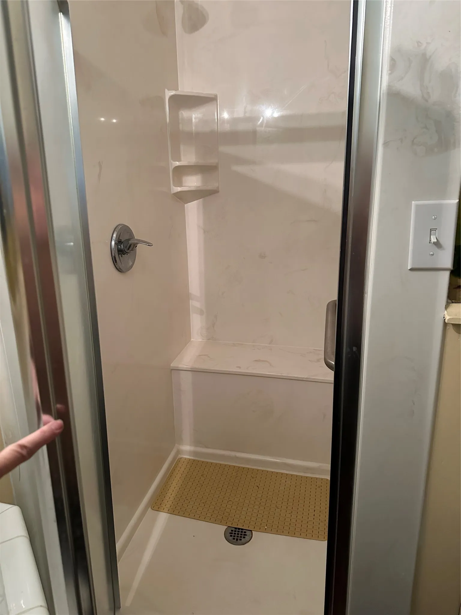 Shower enclosure featuring a built-in bench, integrated corner shelving, and a chrome shower fixture
