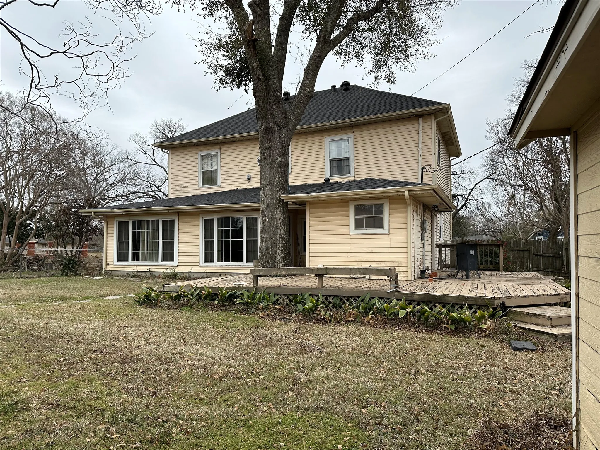 Two-story residence featuring light-colored siding, a dark shingle roof, and multiple windows across its facade