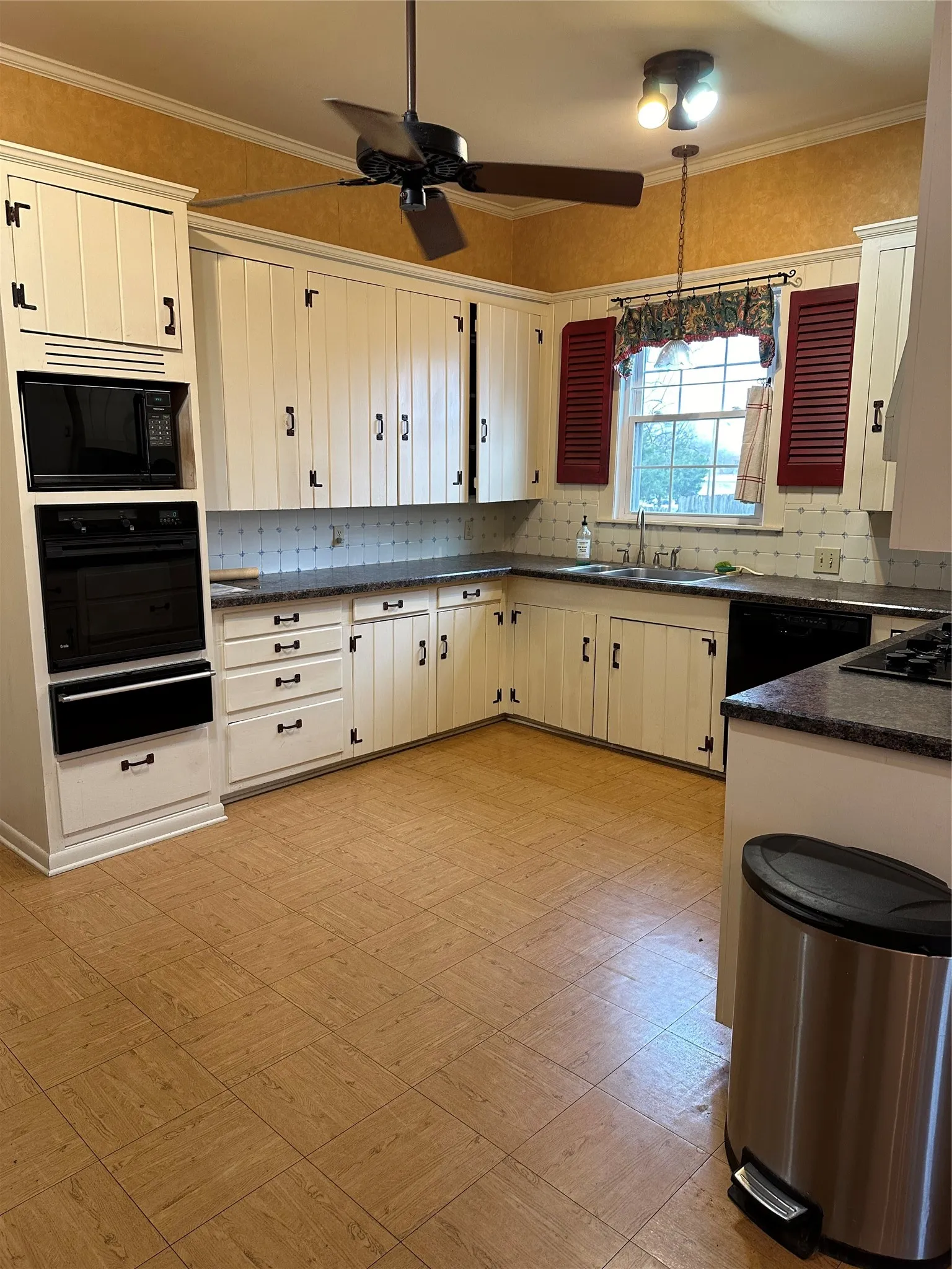 Kitchen featuring white cabinetry with dark hardware, dark countertops, and a tile backsplash