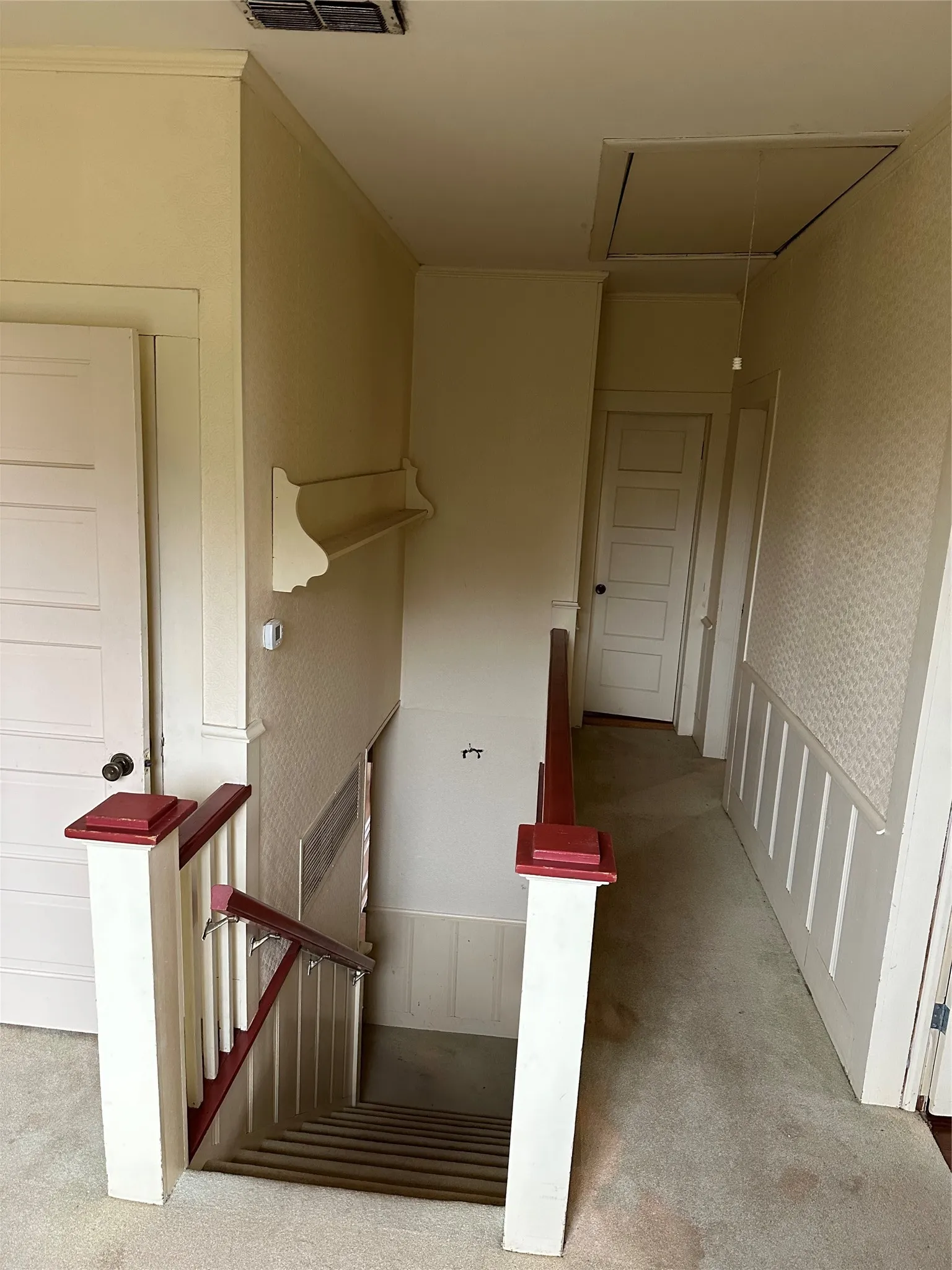 Stairwell featuring white wainscoting and a carpeted upper landing