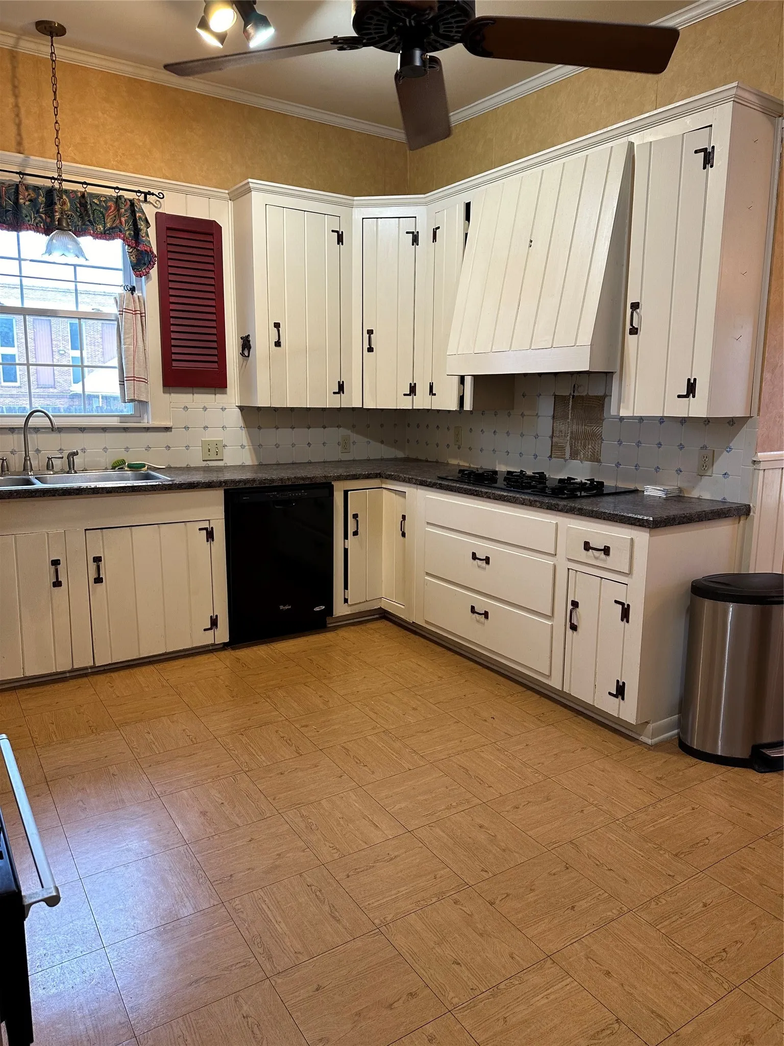 Corner kitchen with white cabinetry, dark countertops, and wood-finish flooring