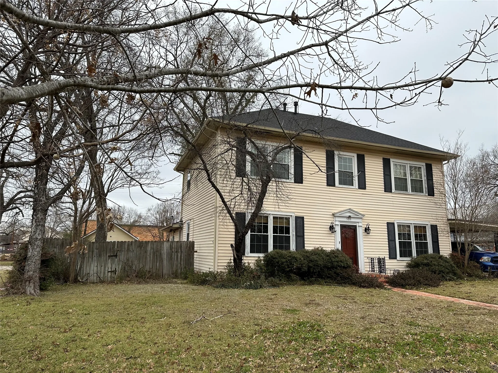 Two-story residence featuring light-colored siding, dark shutters, and a prominent front door