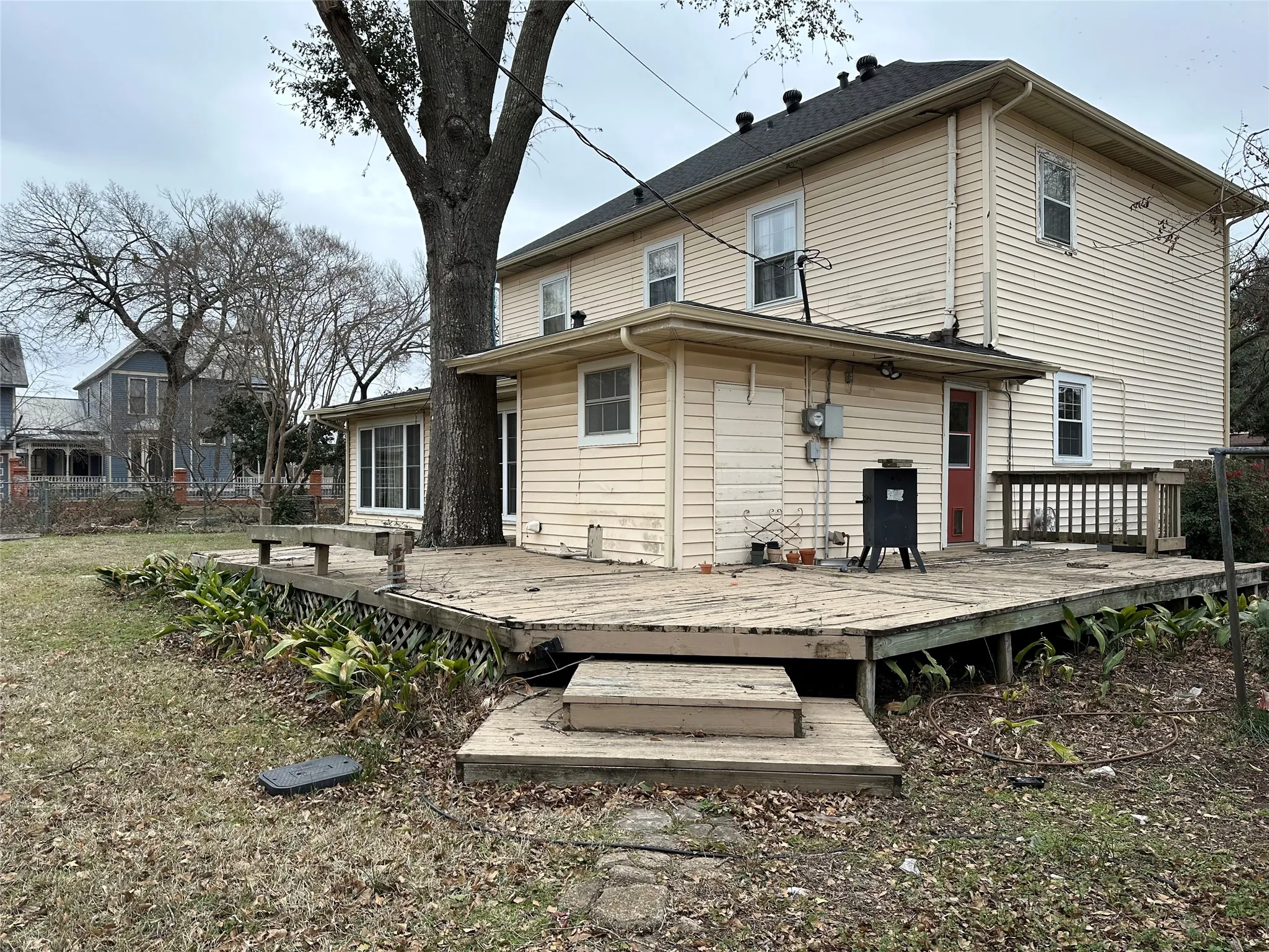 Rear exterior featuring a multi-level wood deck, multiple windows, and light-colored horizontal siding