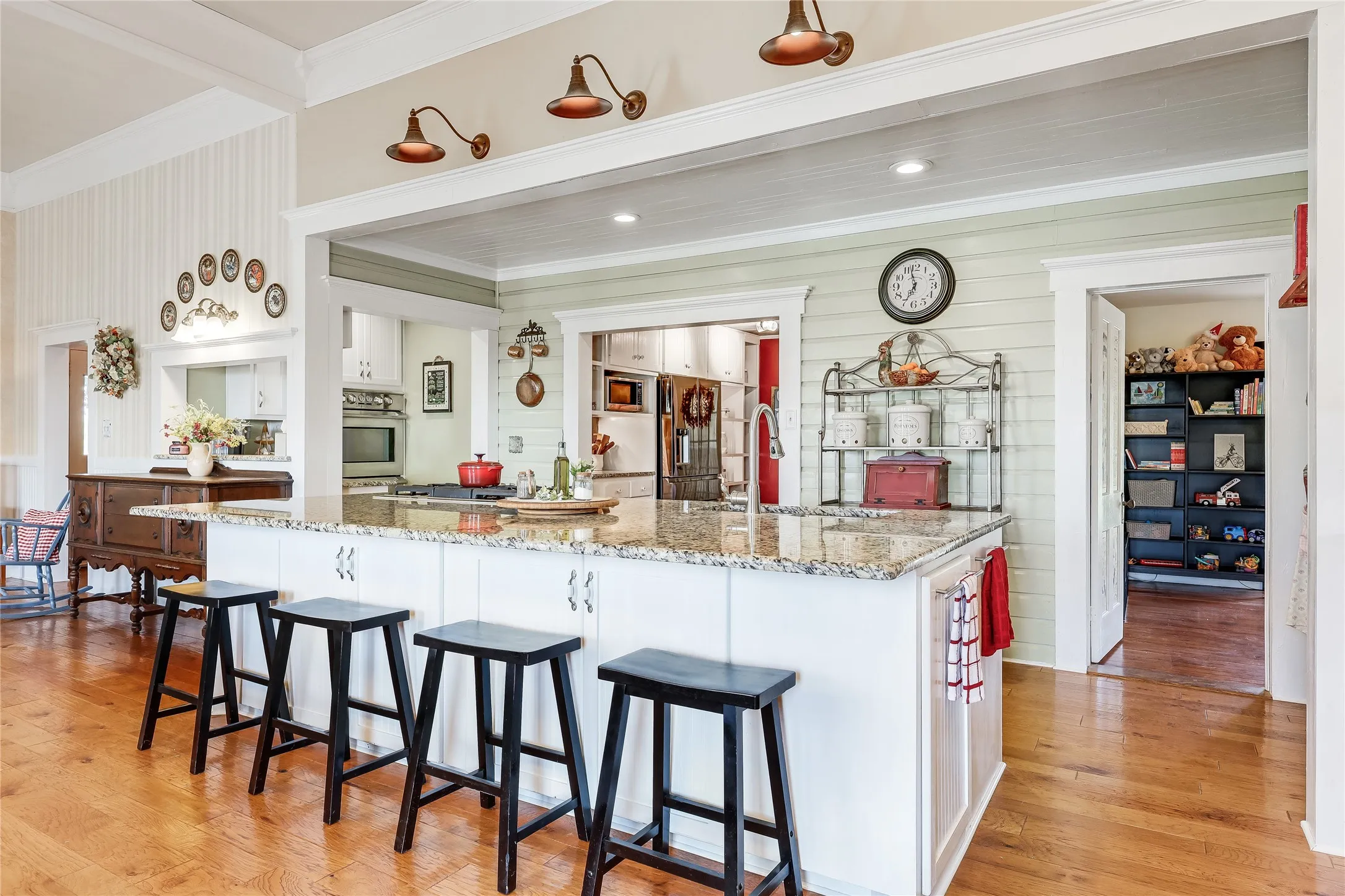 Open-concept kitchen featuring a granite-topped island with white cabinetry, wood-finish flooring, and recessed lighting