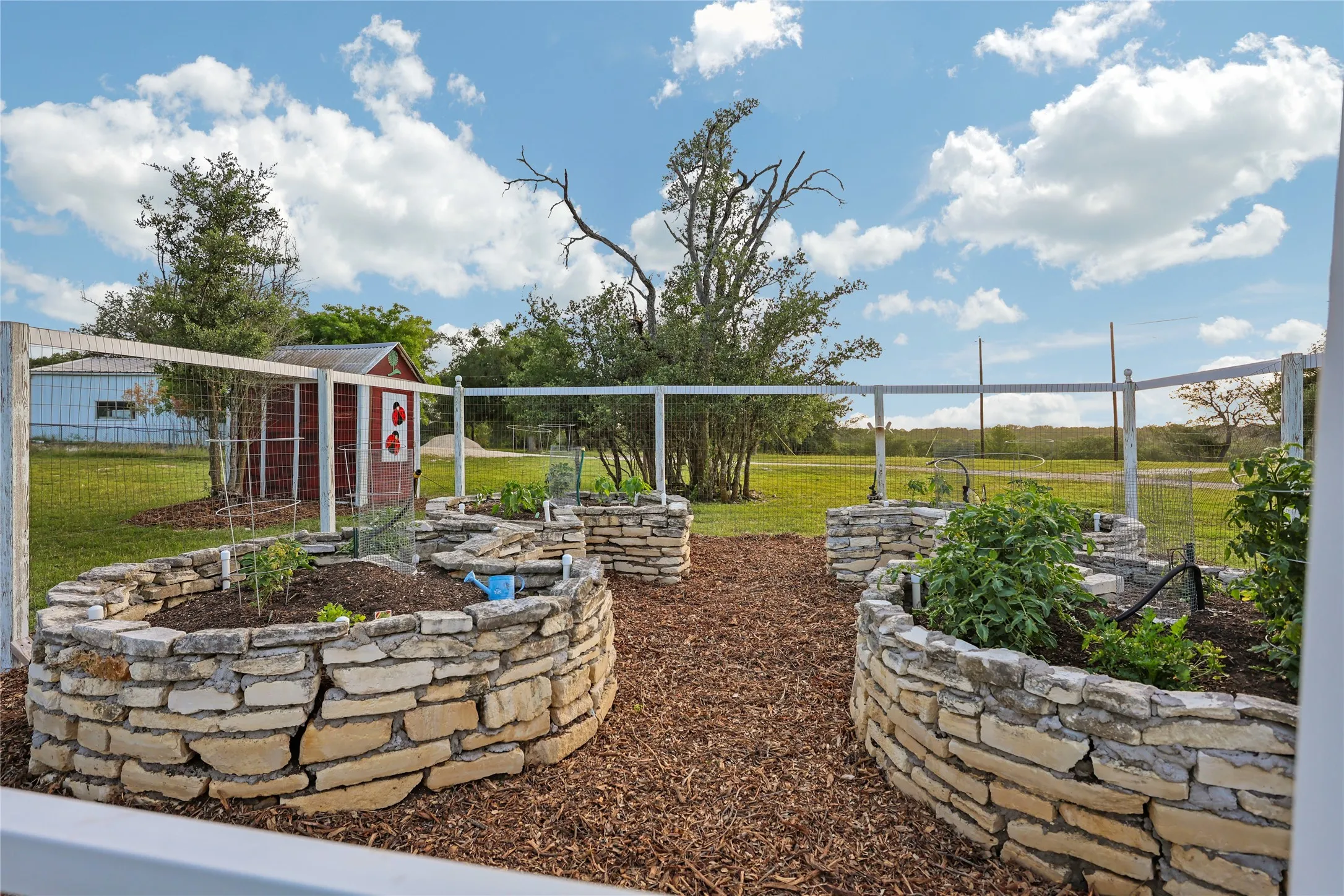 Garden area featuring multiple stone-faced raised beds with plantings