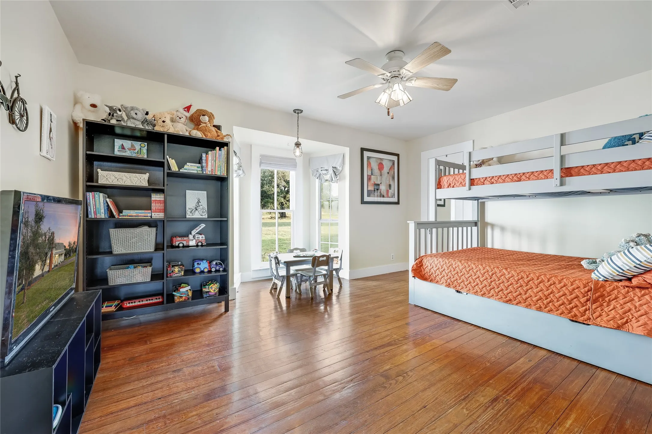 Spacious room featuring rich wood-finish flooring, abundant natural light from multiple windows, a ceiling fan, and recessed lighting