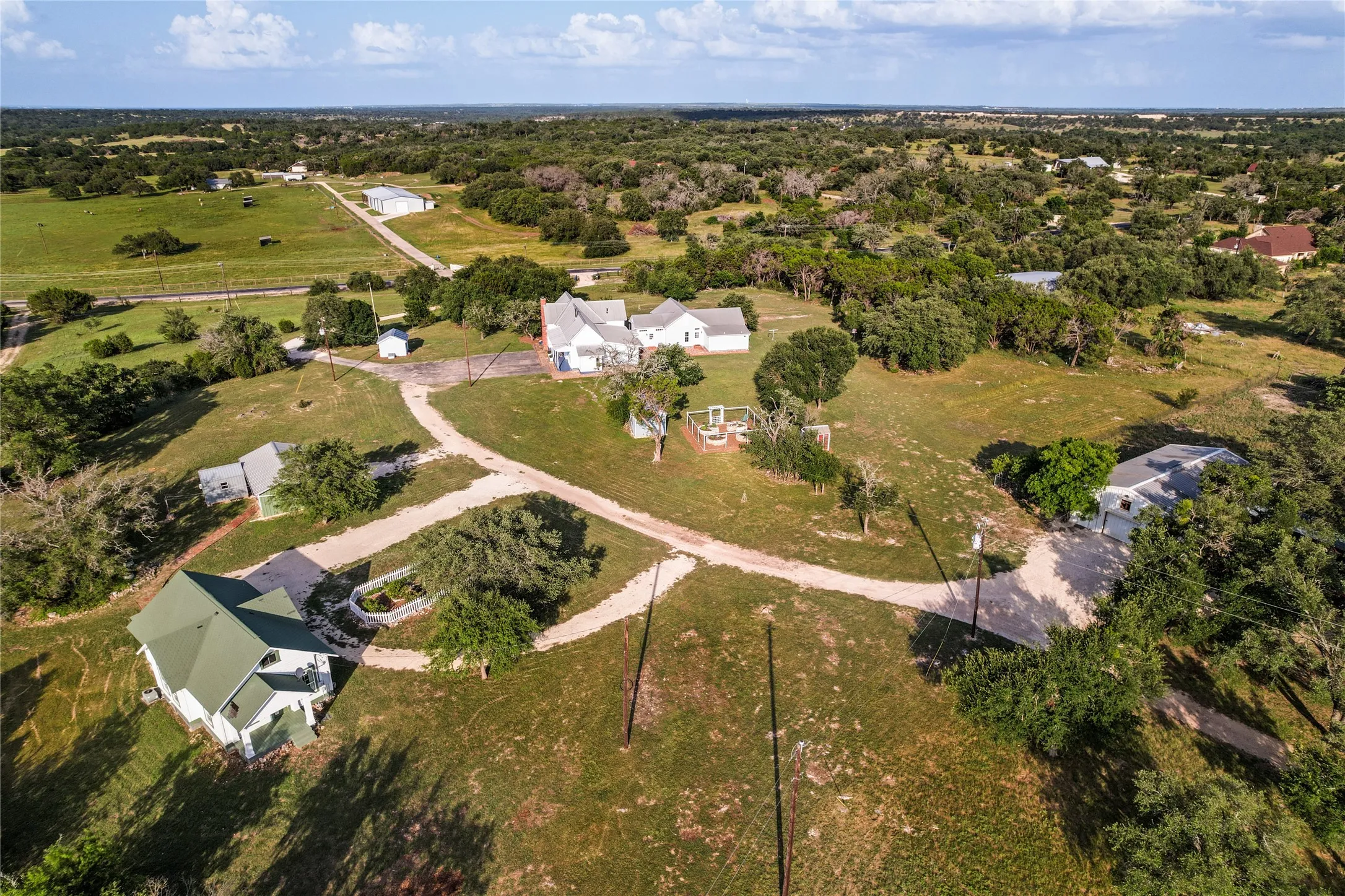 Expansive property featuring multiple structures and a diverse landscape of trees and open grassy areas