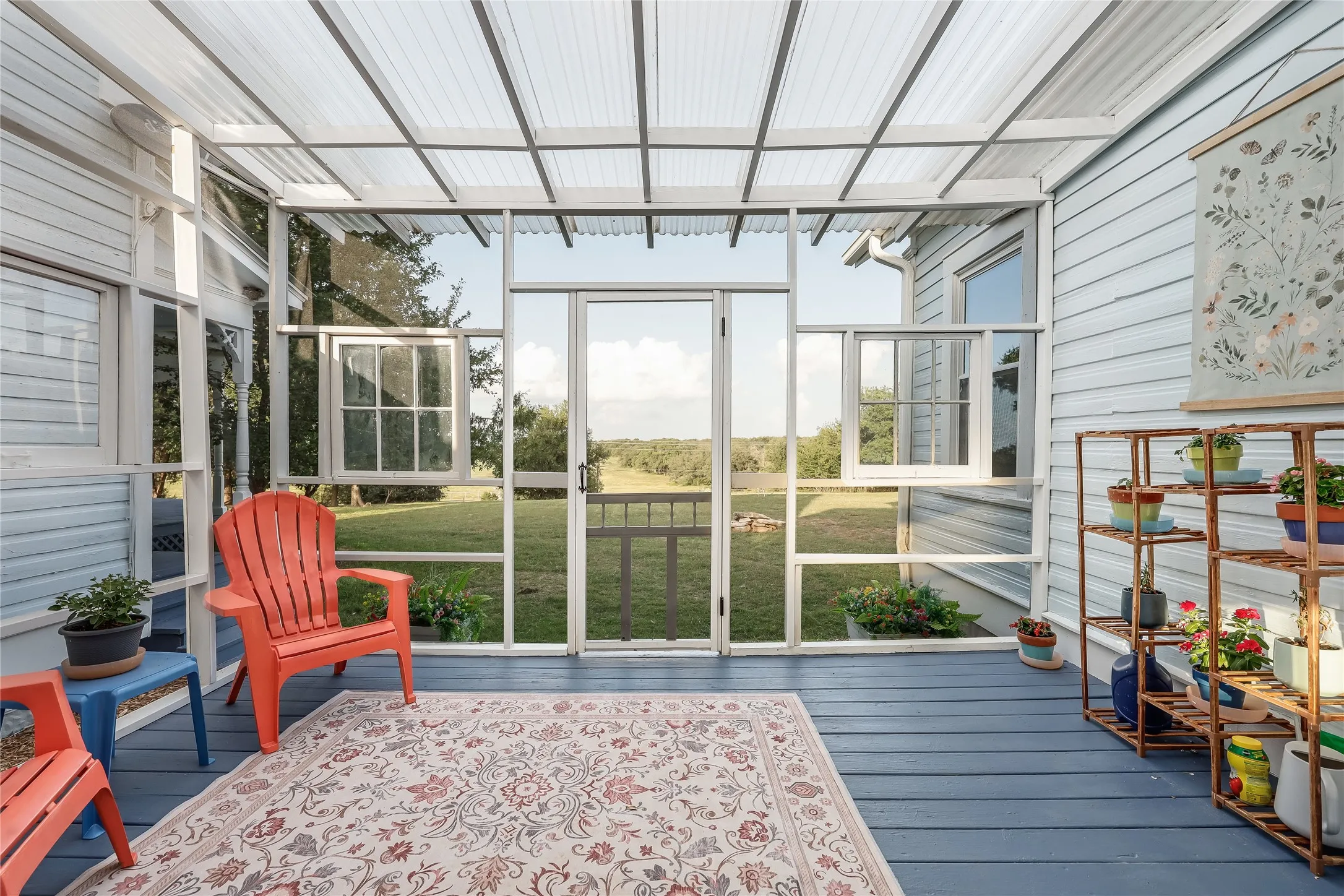 Enclosed sunroom featuring a translucent vaulted ceiling, painted wood flooring, and a sliding glass exterior door
