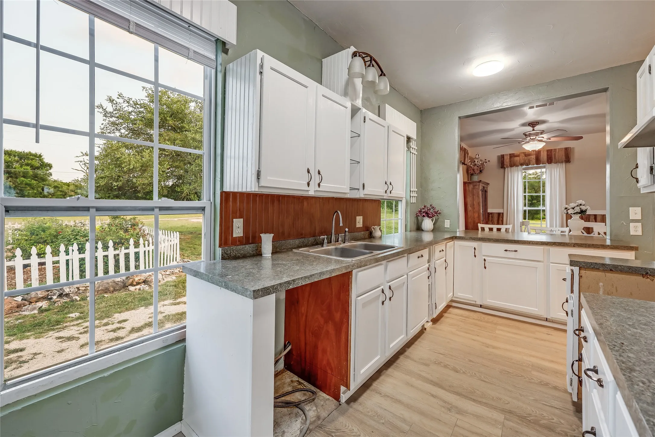 Kitchen featuring white cabinetry, wood-finish flooring, a double basin sink, and ample countertop space
