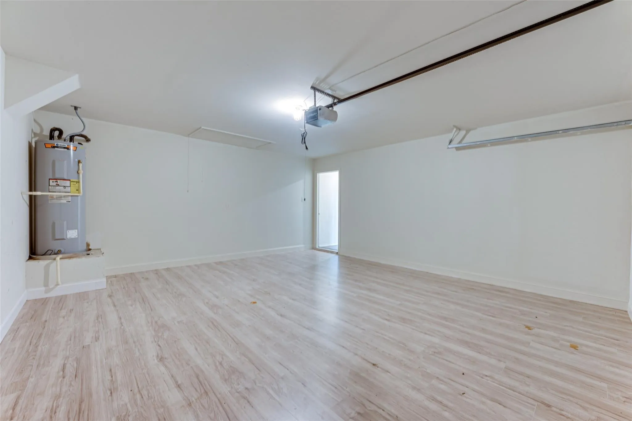 Spacious utility room featuring wood-finish flooring, white painted walls, and a water heater