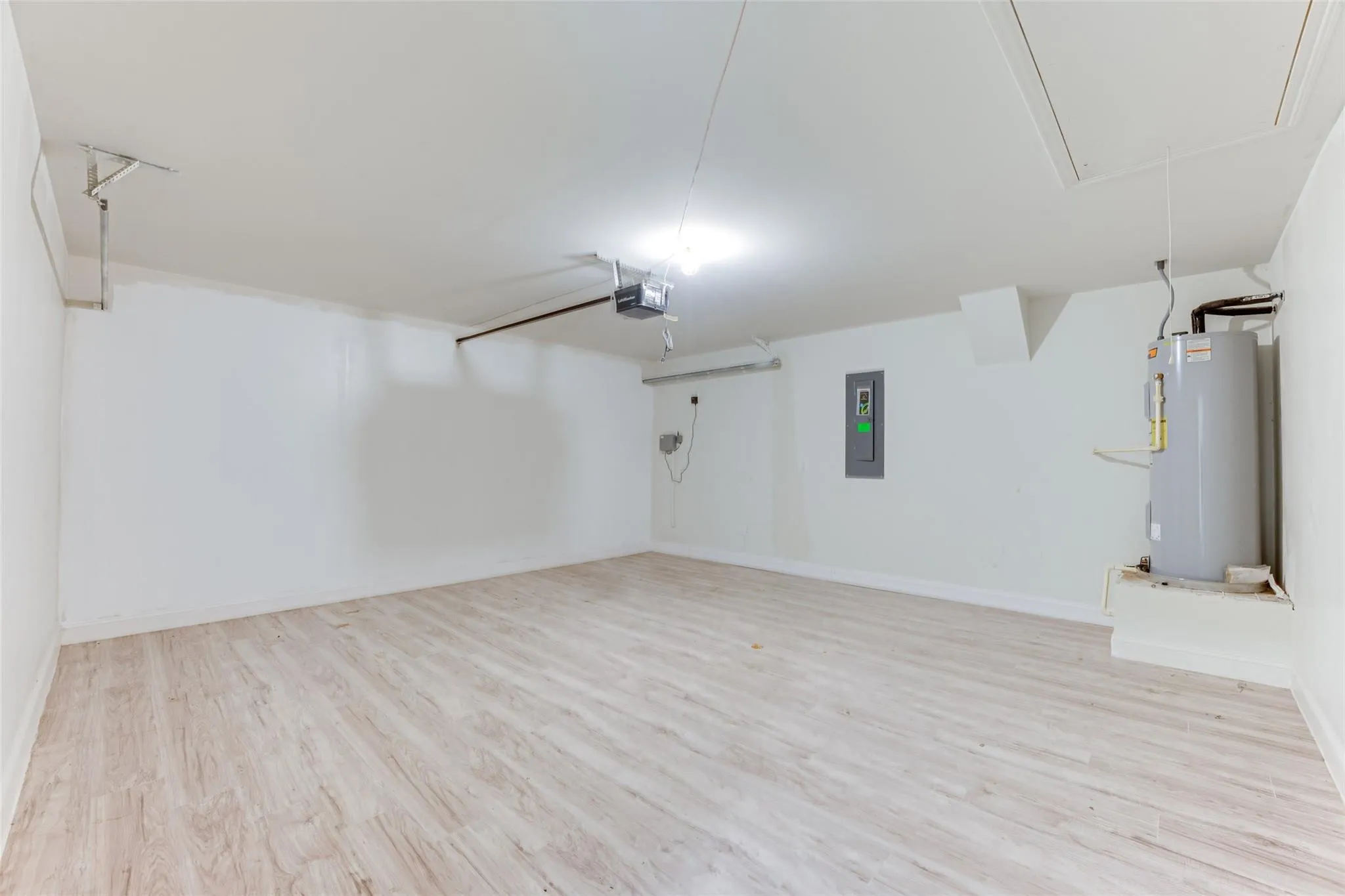 Spacious interior with light wood-finish flooring, white walls, and bright overhead lighting