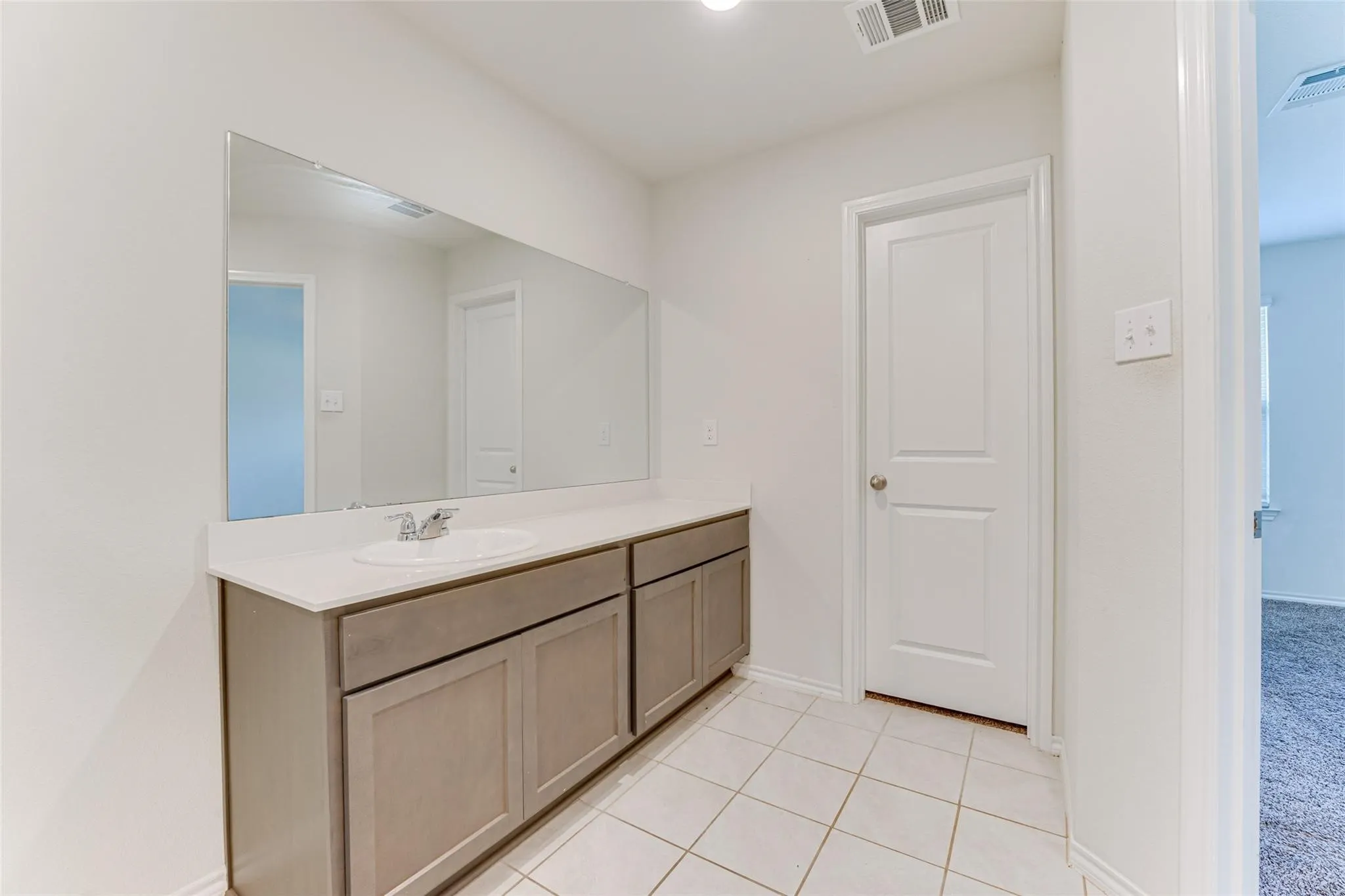 Vanity area featuring an integrated sink, light-toned countertop, and expansive wall-mounted mirror