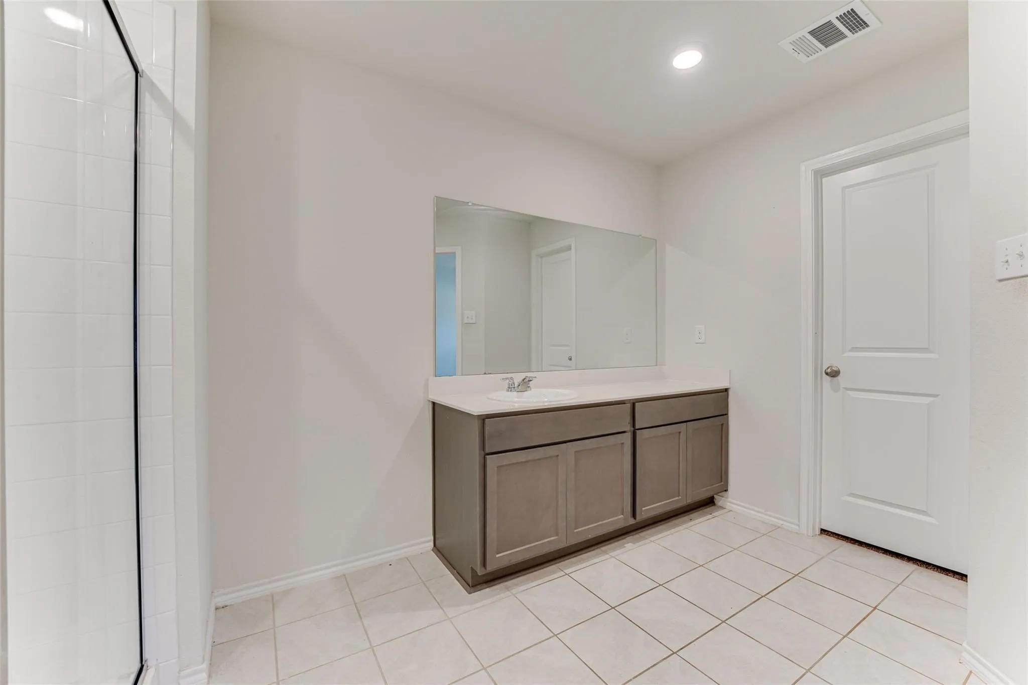 Bathroom vanity featuring a single basin sink, light-toned countertop, and dark wood-finish cabinetry