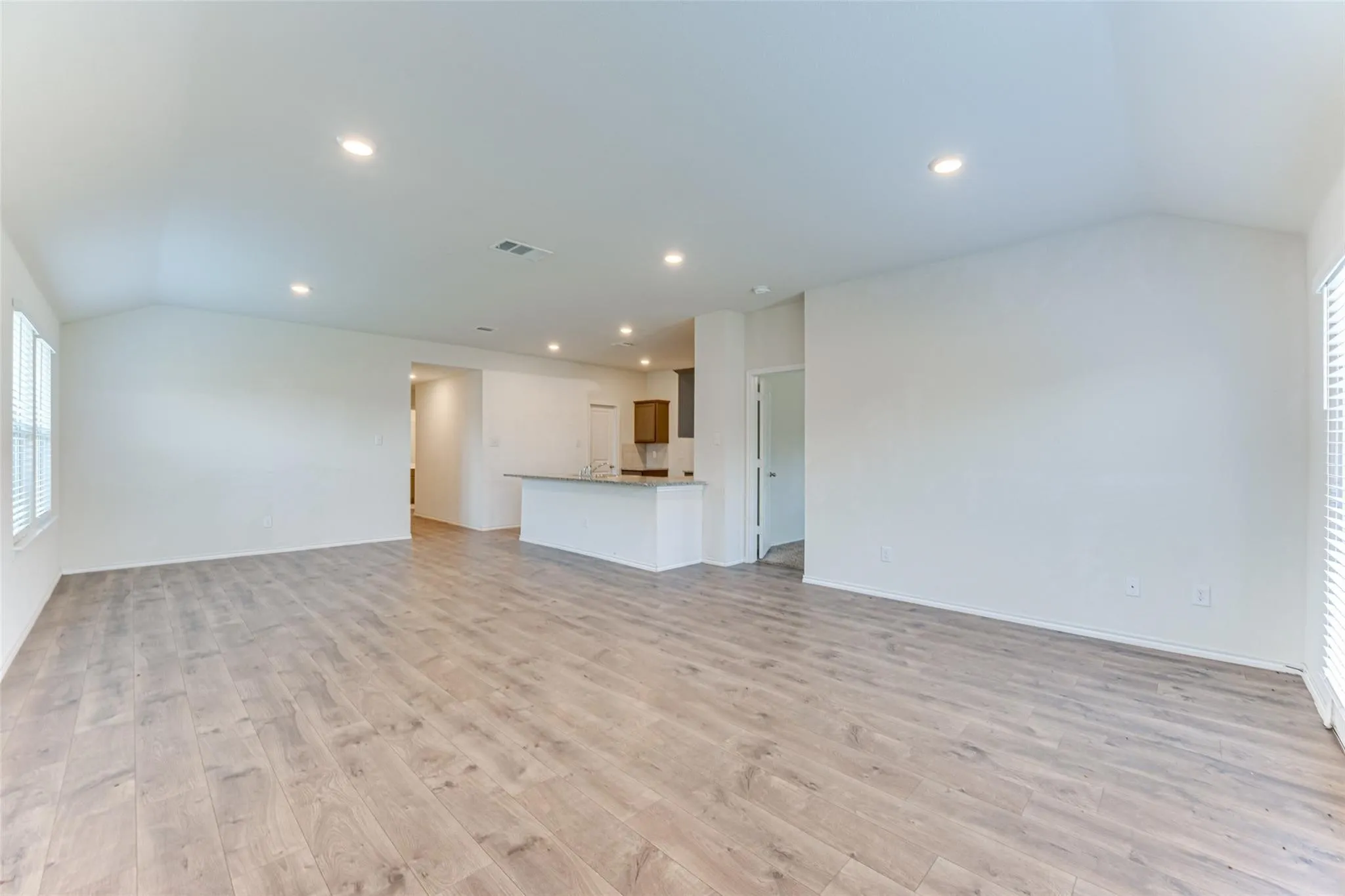 Spacious room featuring wood-finish flooring, recessed lighting, and white walls