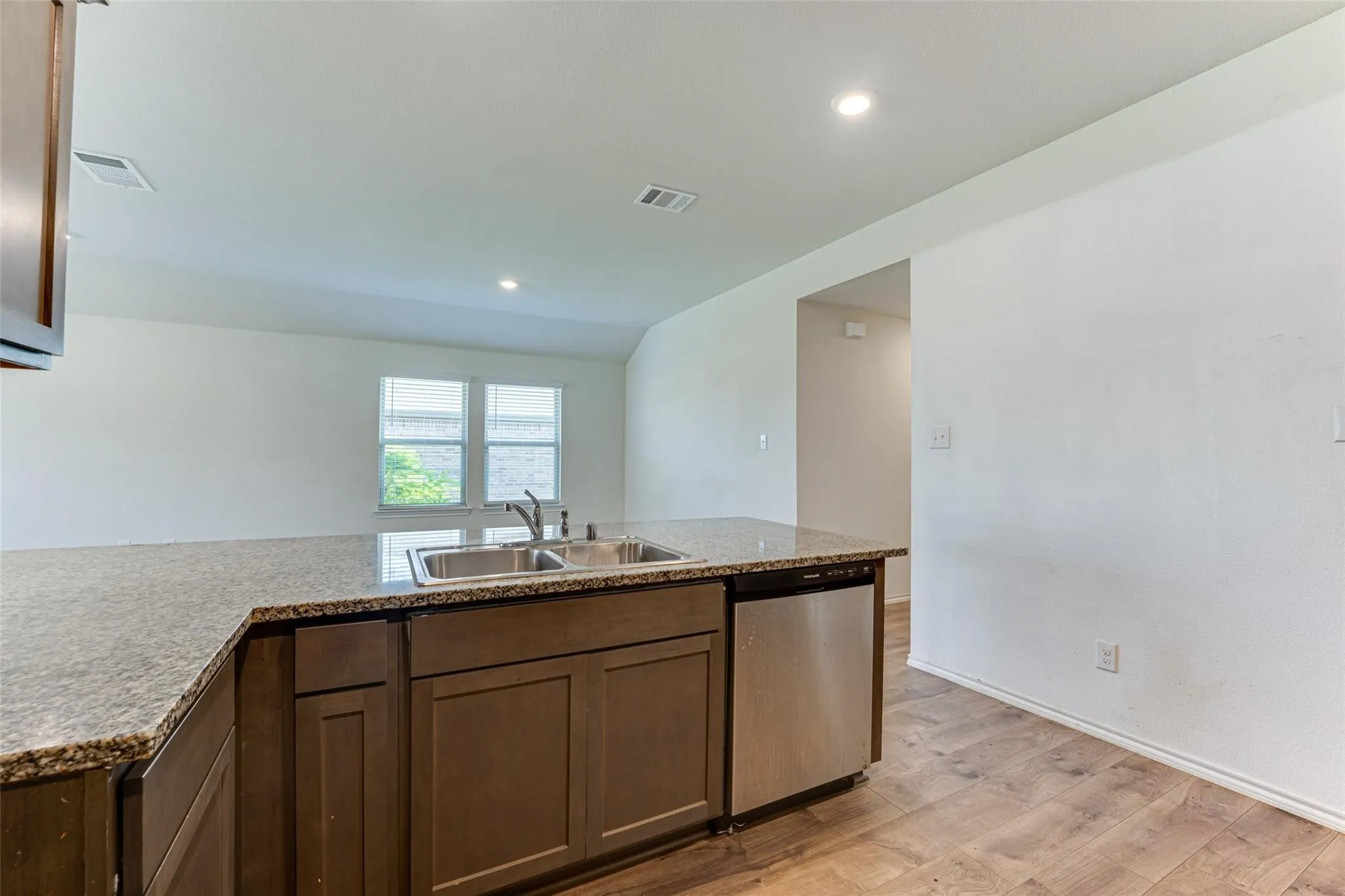 Kitchen island with granite countertops, integrated double basin sink, and stainless steel dishwasher