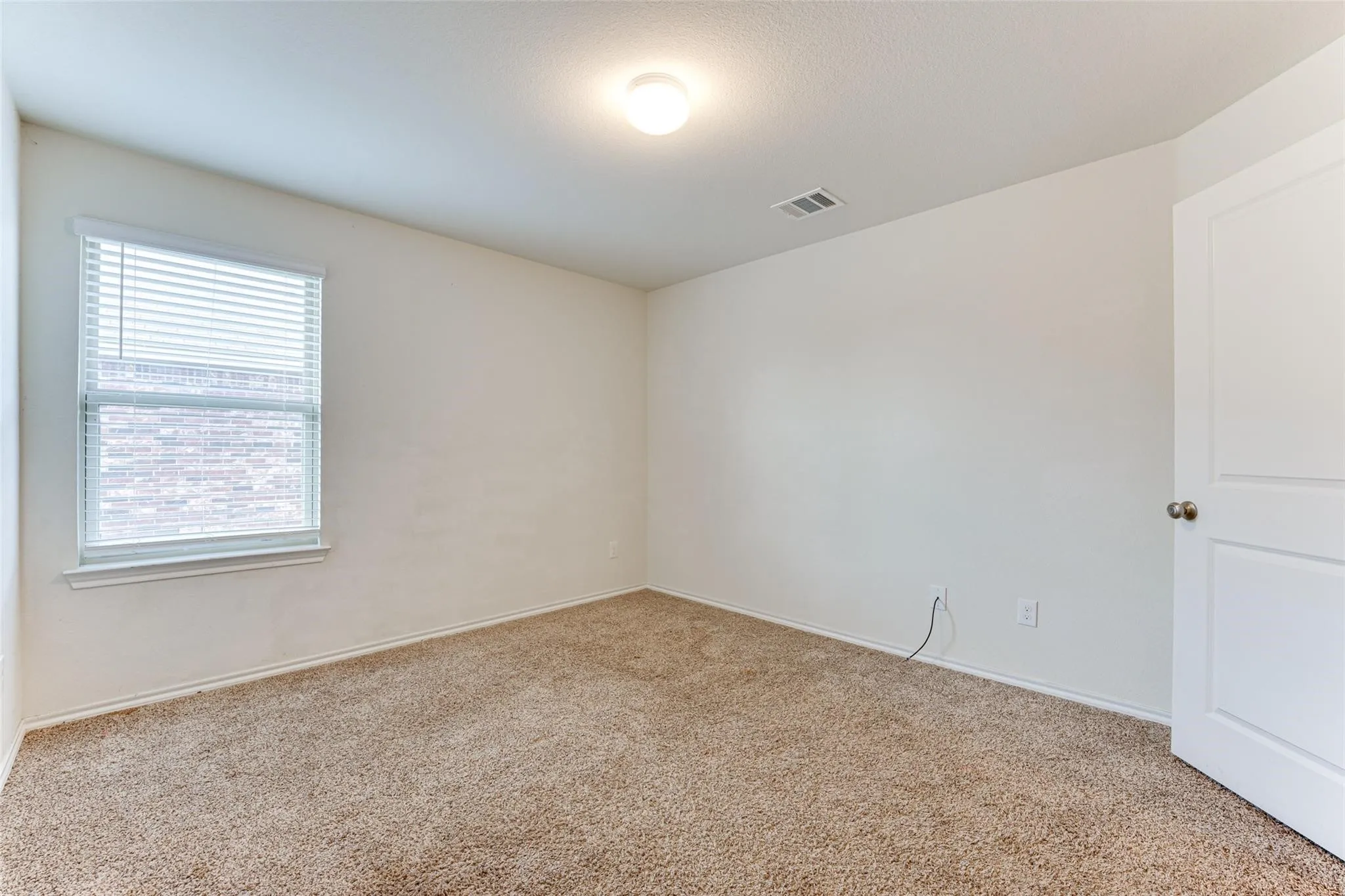 Carpeted room with a single window featuring horizontal blinds