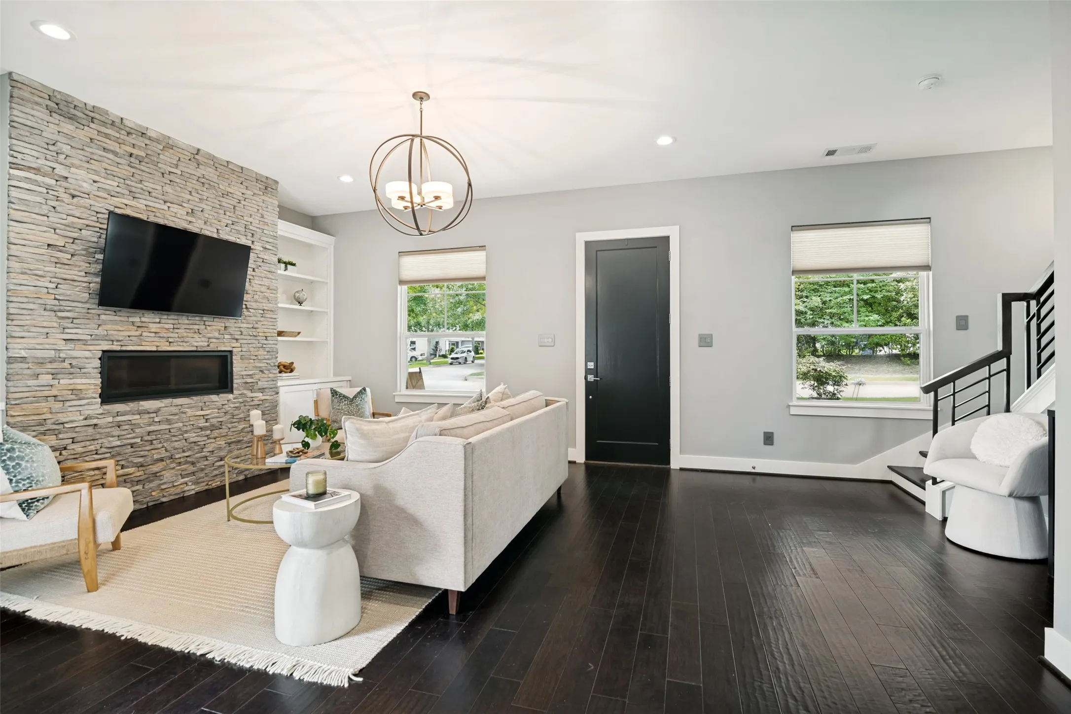 Open-concept living space featuring wood flooring and stone fireplace