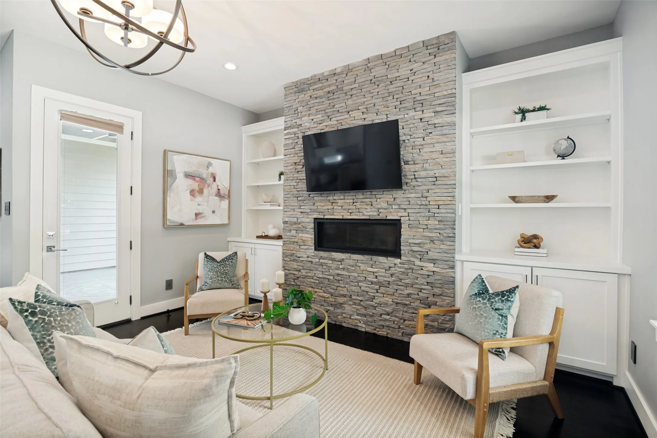 Spacious living area anchored by a stunning floor-to-ceiling stone fireplace with beautiful custom built-ins on either side