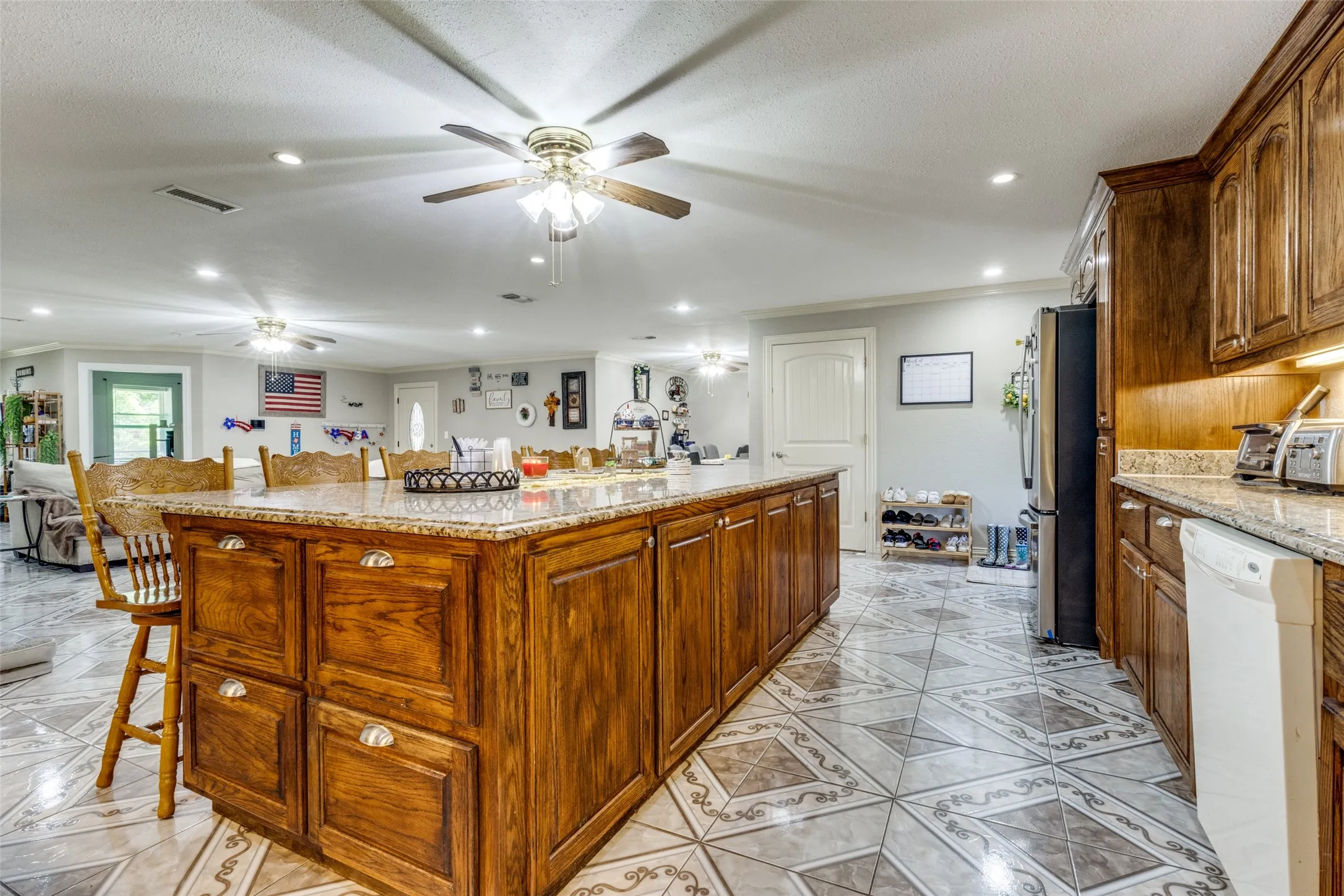 Kitchen with a breakfast bar area, open floor plan, recessed lighting, dishwasher, and light stone countertops