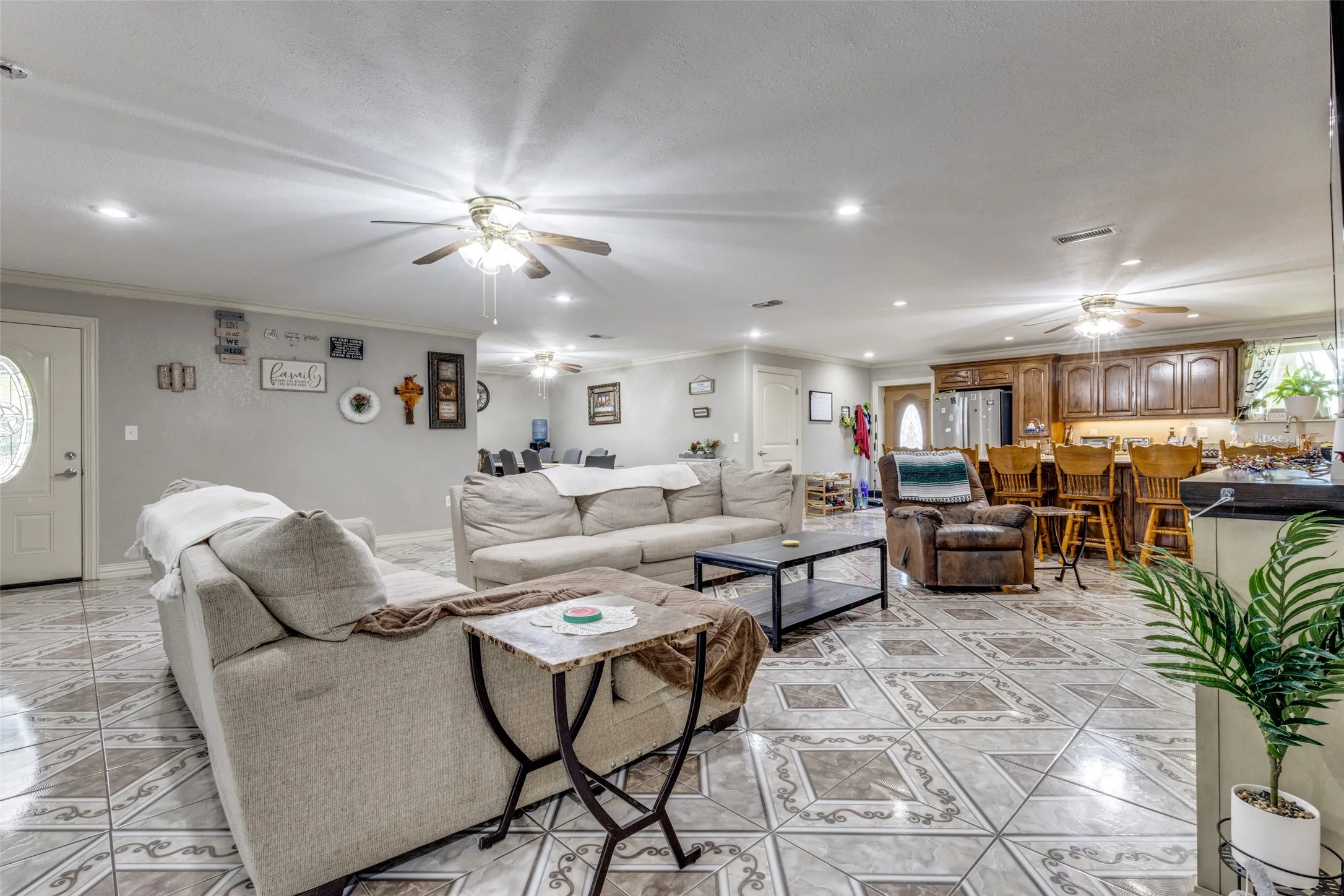 Living area featuring recessed lighting, crown molding, light tile patterned floors, healthy amount of natural light, and a ceiling fan