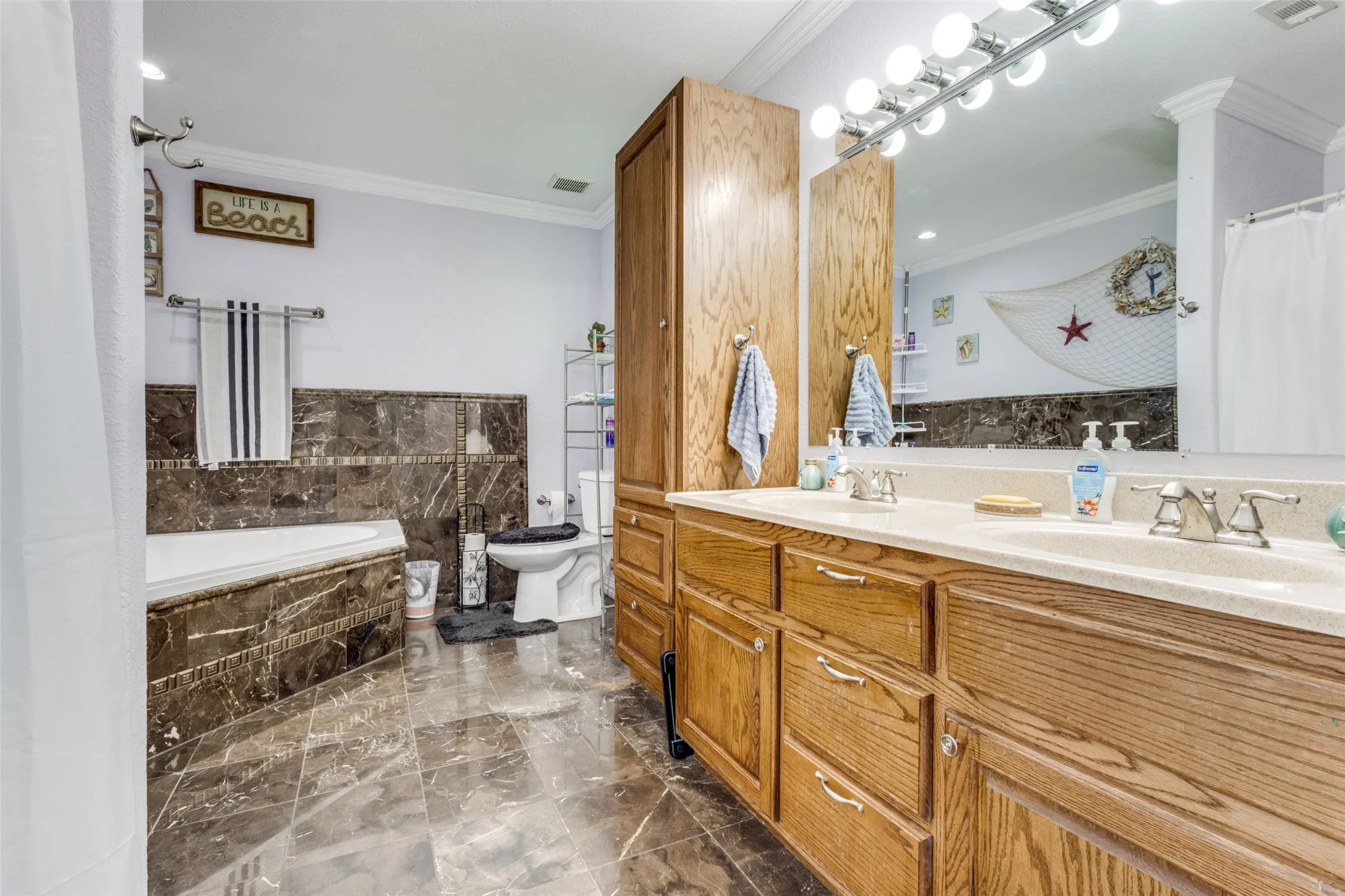Full bathroom with crown molding, a garden tub, and dark marble finish flooring