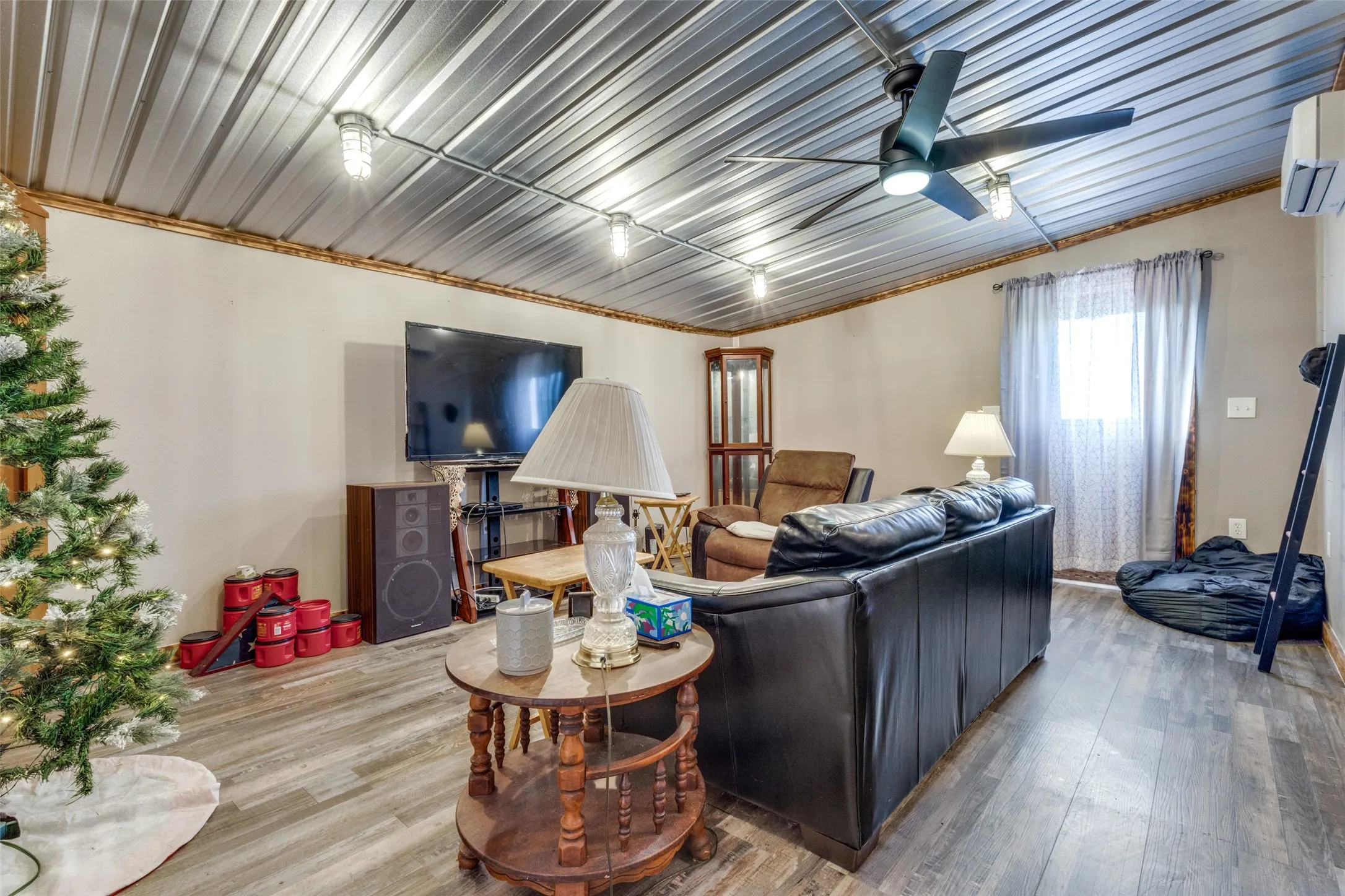 Living room with a ceiling fan, wood finished floors, and a wall mounted AC