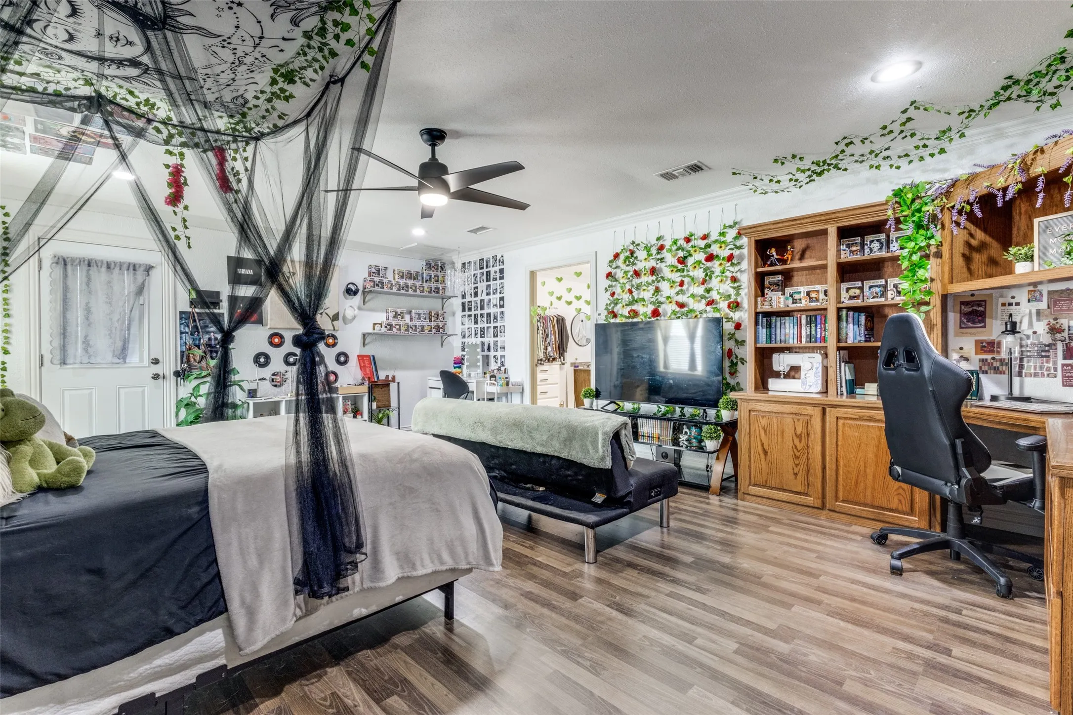 Bedroom with ornamental molding, wood finished floors, and an office area