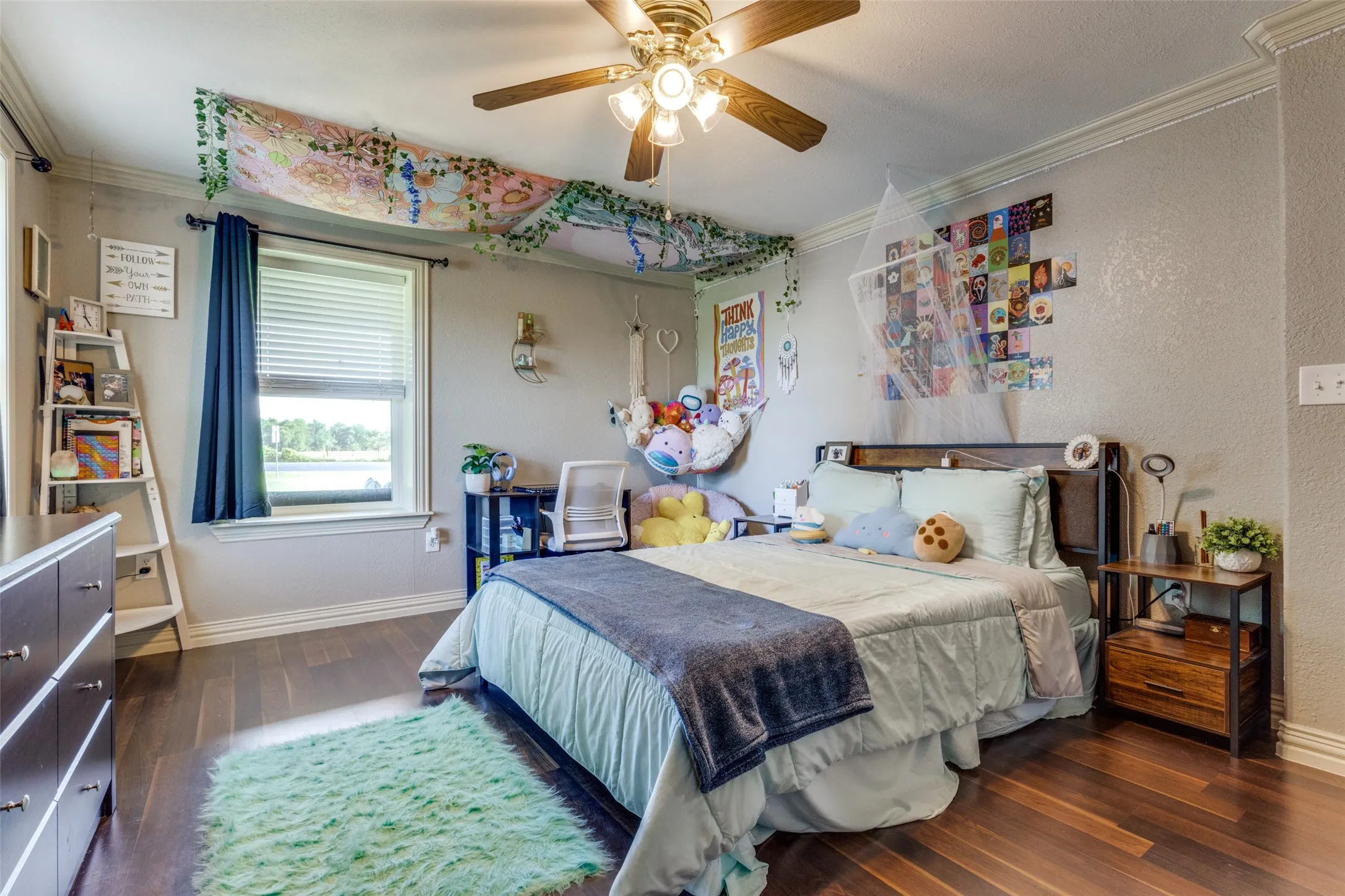 Bedroom featuring dark wood-type flooring, crown molding, a textured wall, and a ceiling fan