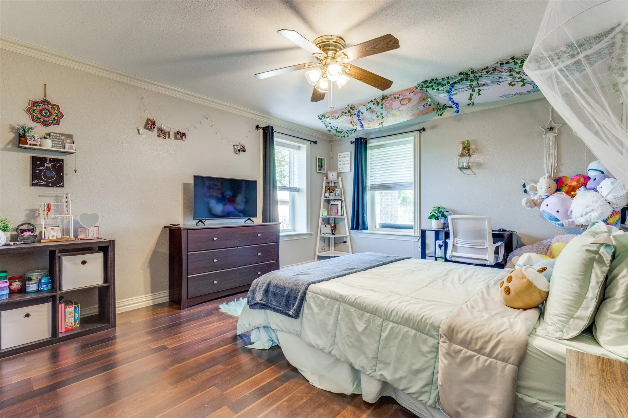 Bedroom with crown molding, wood finished floors, and ceiling fan