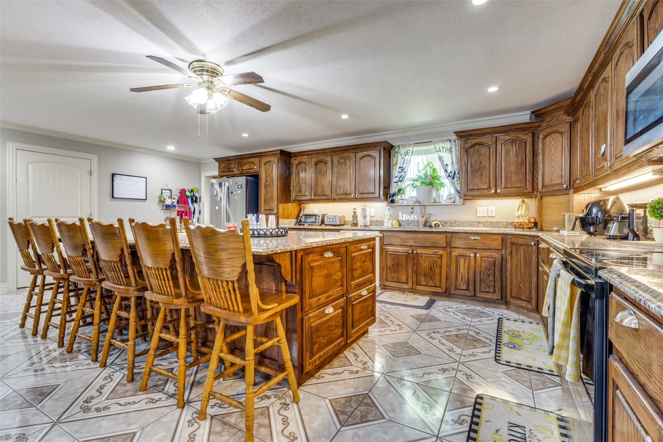 Kitchen with a center island, recessed lighting, brown cabinetry, light stone countertops, and a breakfast bar area