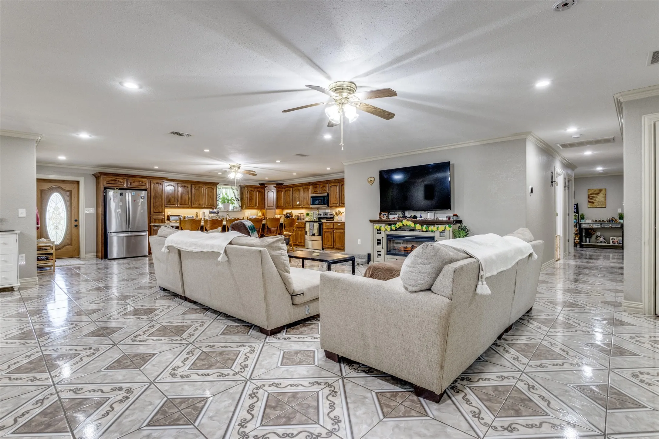 Living room with recessed lighting, ornamental molding, a glass covered fireplace, and a ceiling fan