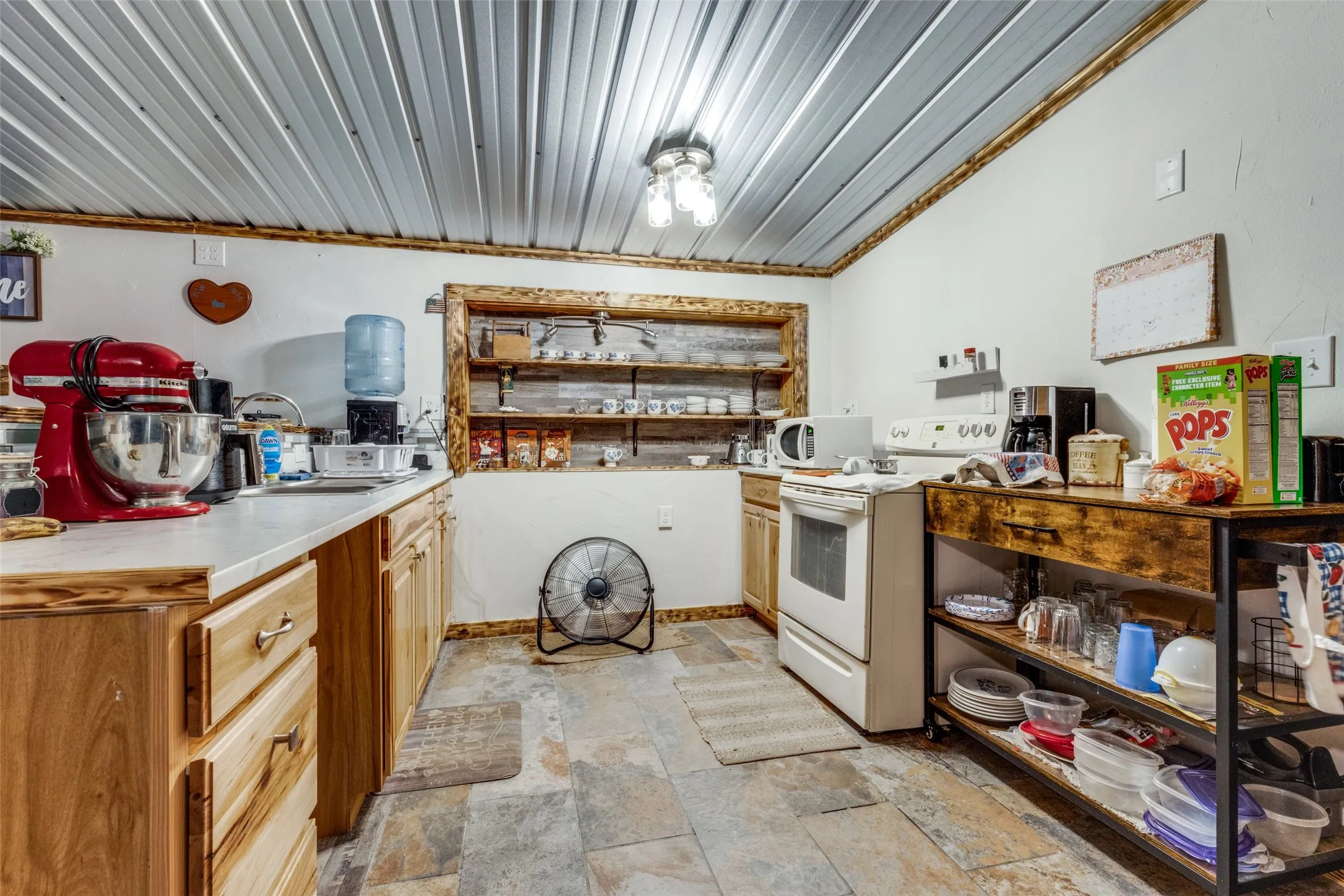 Kitchen featuring light countertops, white appliances, light stone finish flooring, and open shelves